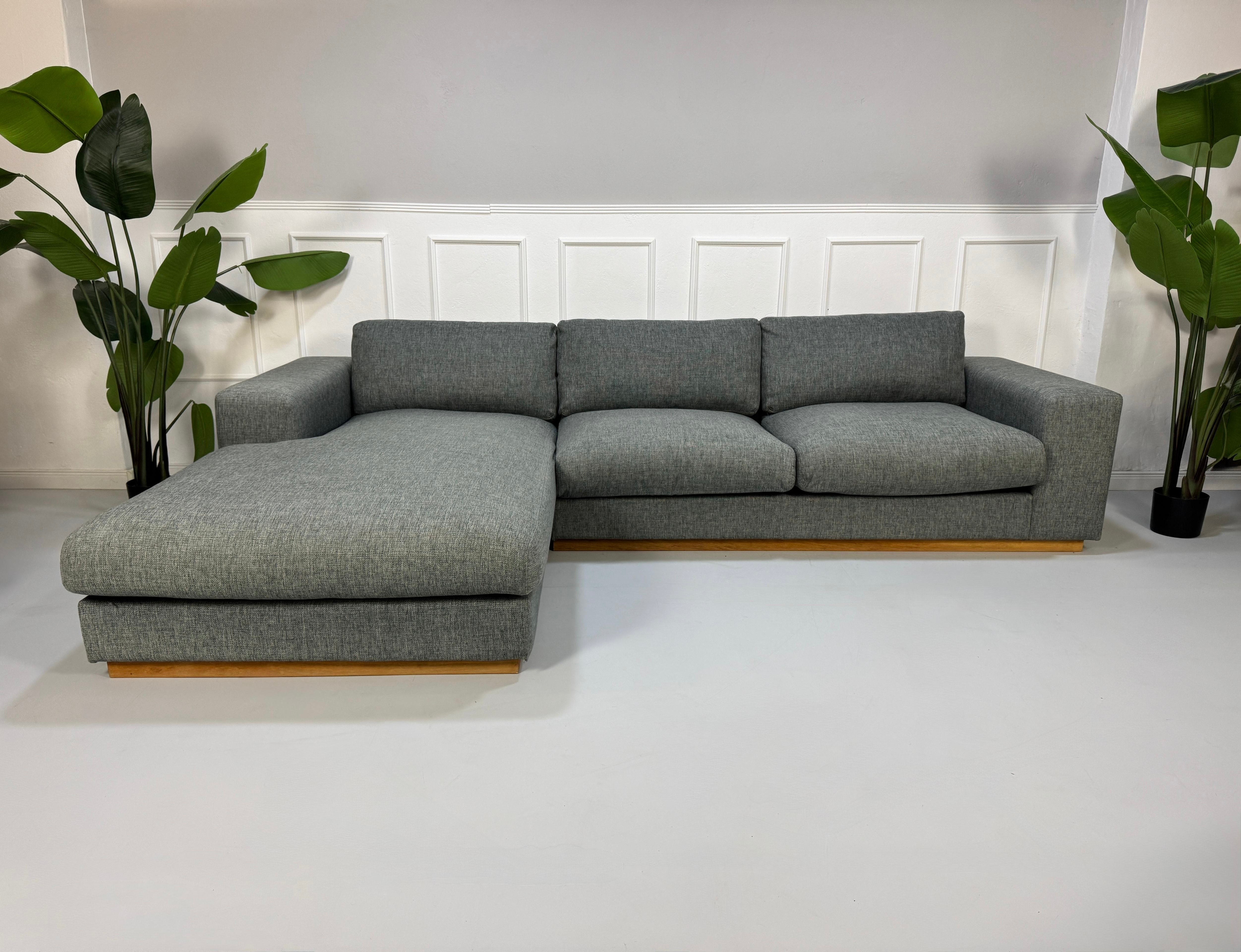 Refurbished graues Bolia Sepia Designer Stoff Sofa vor einer Wand, stilvoll und modern eingerichtet.