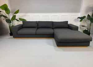 Gebrauchtes graues Bolia Sepia Designer Stoff Sofa mit Hocker vor einer Wand, stilvoll und modern eingerichtet.