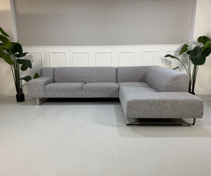 Gebrauchtes graues Bolia Seville Designer Stoff Ecksofa vor einer Wand, stilvoll und modern eingerichtet.