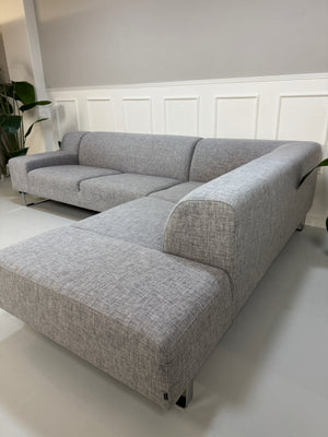 Gebrauchtes graues Bolia Seville Designer Stoff Ecksofa vor einer Wand, stilvoll und modern eingerichtet.