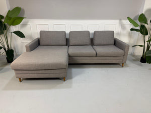 Gebrauchtes graues Bolia Designer Stoff Sofa vor einer Wand, stilvoll und modern eingerichtet.