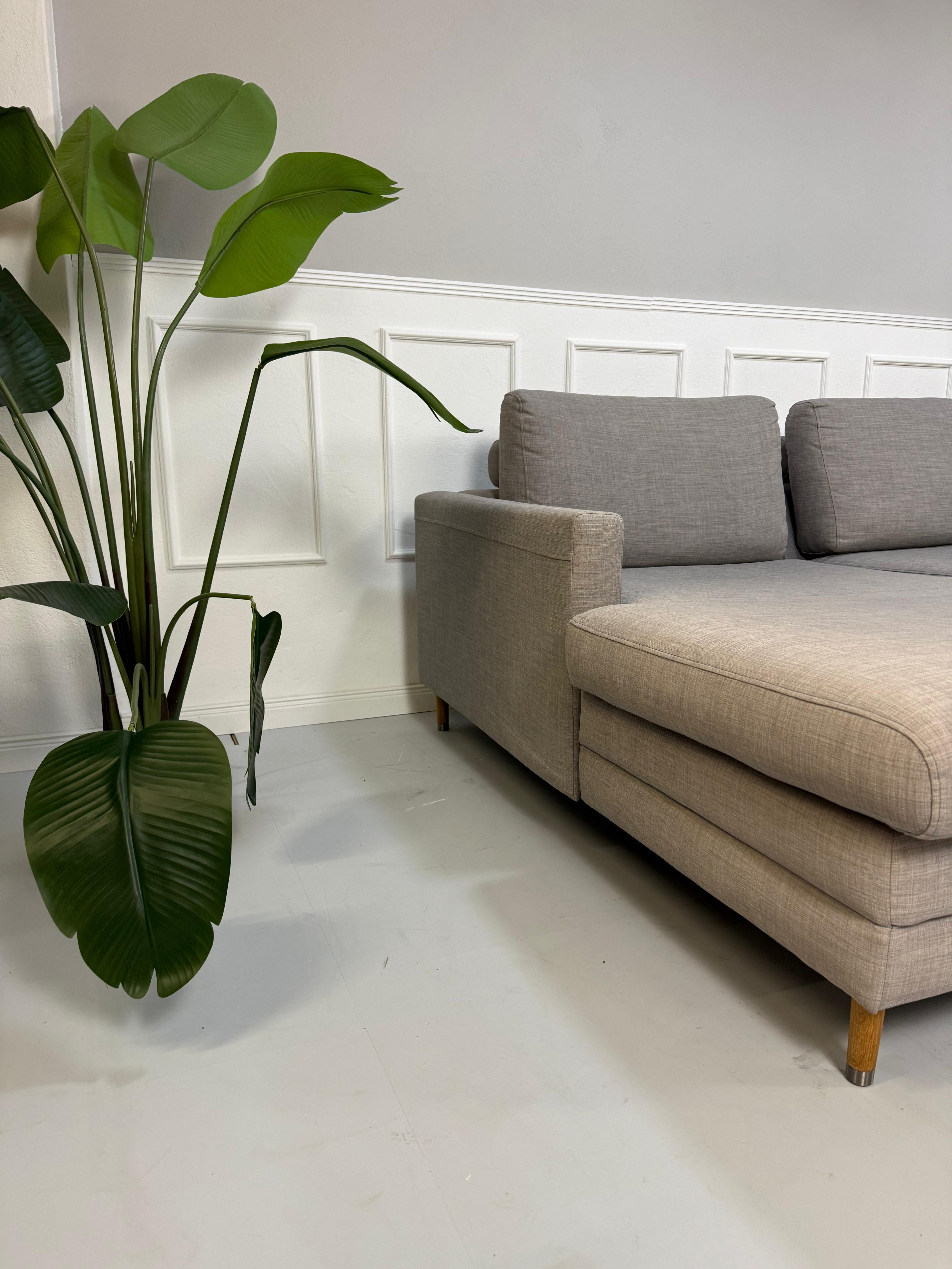 Gebrauchtes graues Bolia Designer Stoff Sofa vor einer Wand, stilvoll und modern eingerichtet.