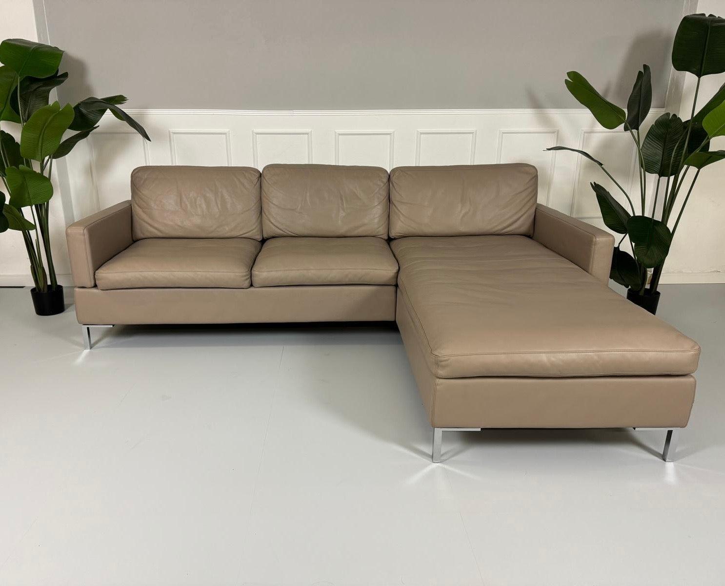 Gebrauchtes Brühl Alba Leder Sofa in Schlamm Farbe vor einer Wand, stilvoll und modern eingerichtet.