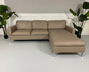 Gebrauchtes Brühl Alba Leder Sofa in Schlamm Farbe vor einer Wand, stilvoll und modern eingerichtet.