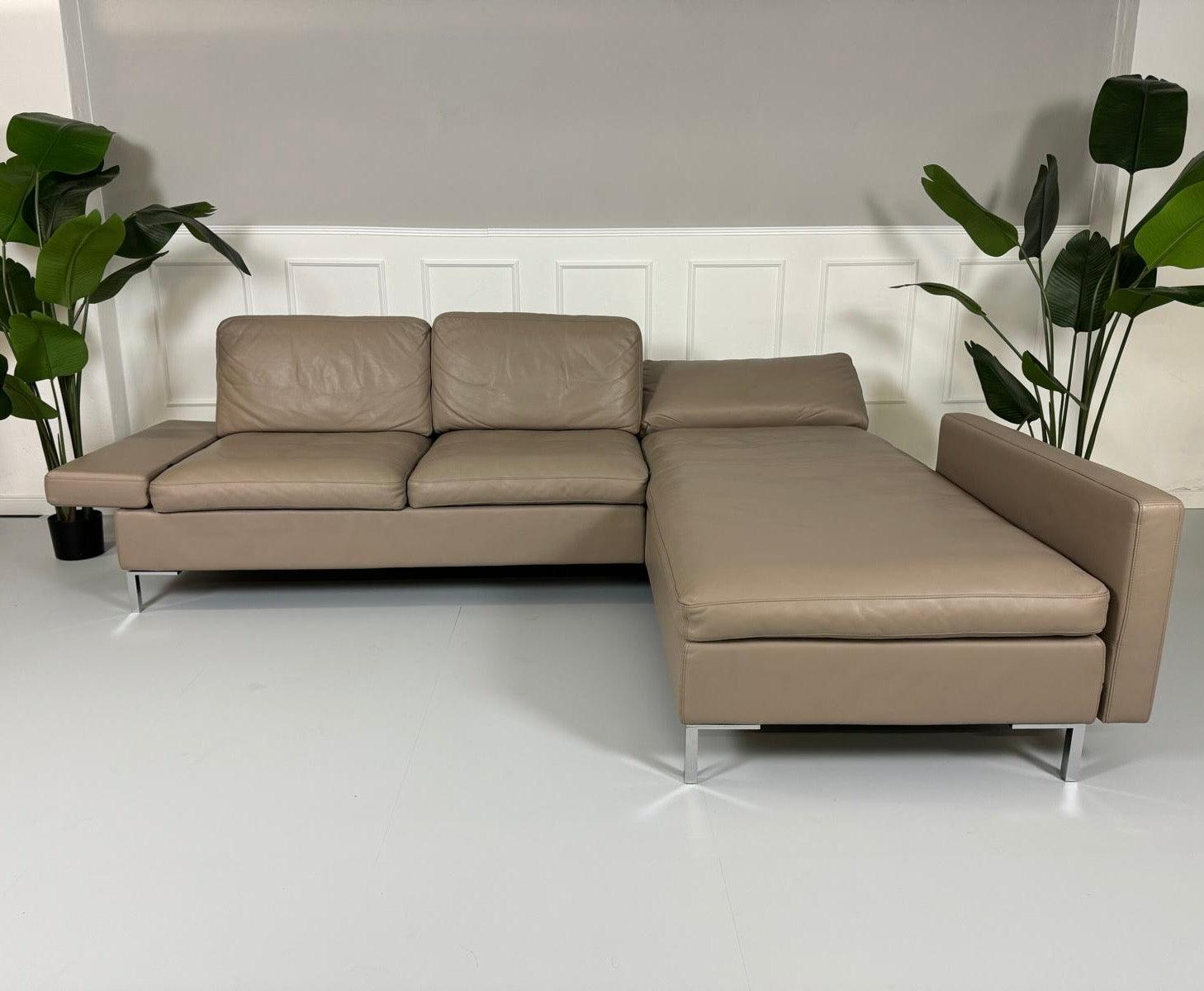 Gebrauchtes Brühl Alba Leder Sofa in Schlamm Farbe vor einer Wand, stilvoll und modern eingerichtet.