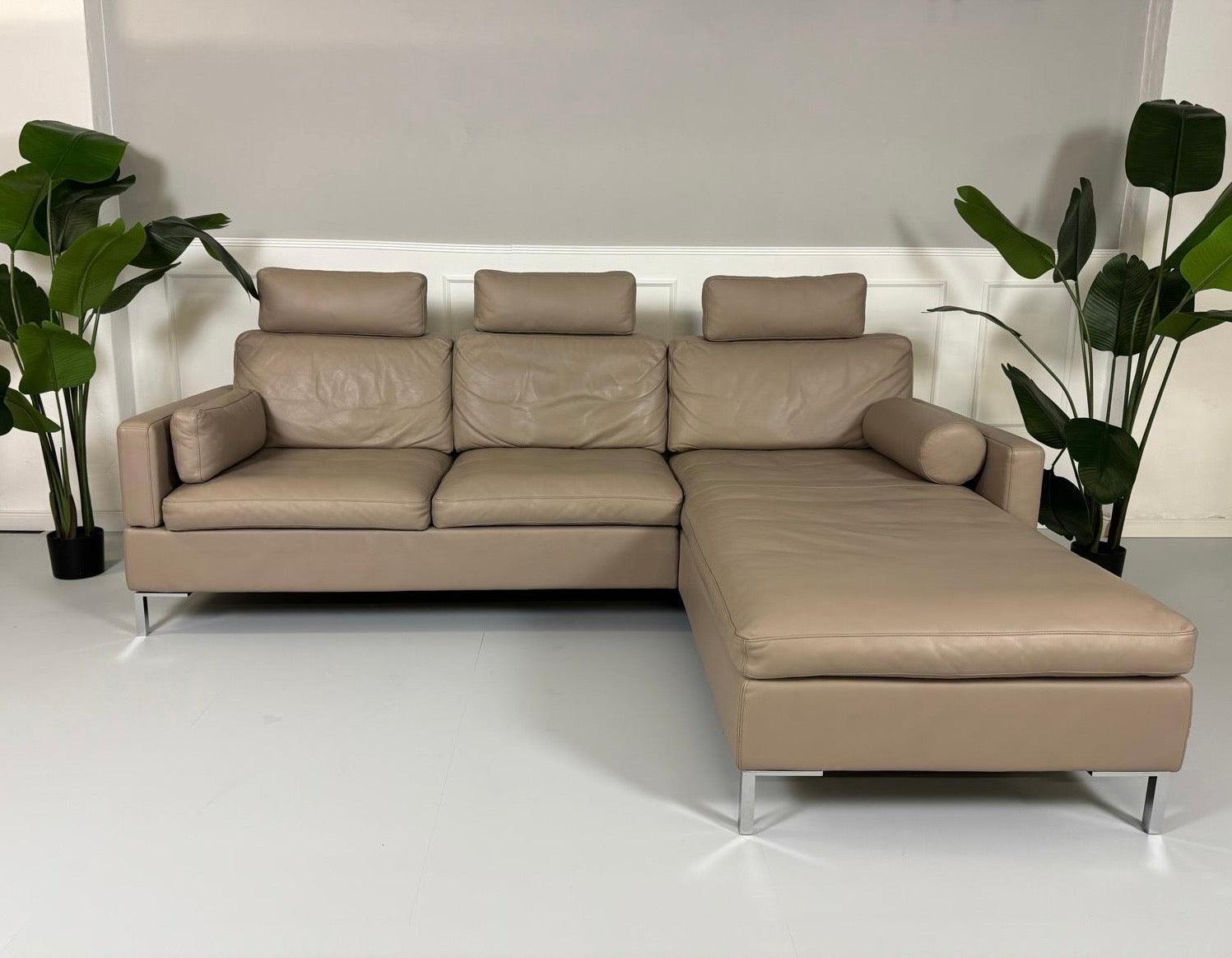 Gebrauchtes Brühl Alba Leder Sofa in Schlamm Farbe vor einer Wand, stilvoll und modern eingerichtet.