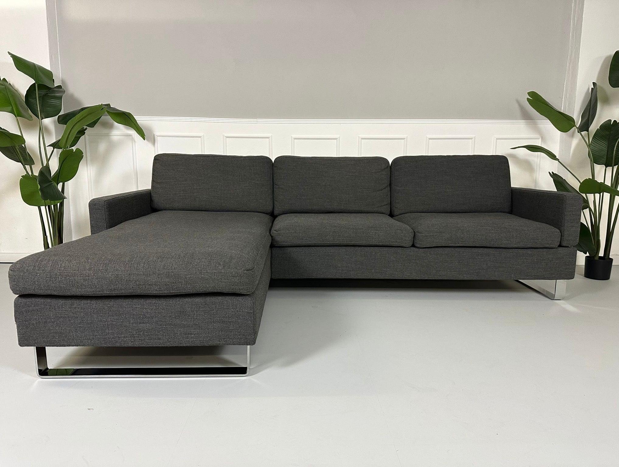 Gebrauchtes Brühl Alba Stoff Sofa in Anthrazit vor einer Wand, stilvoll und modern eingerichtet.