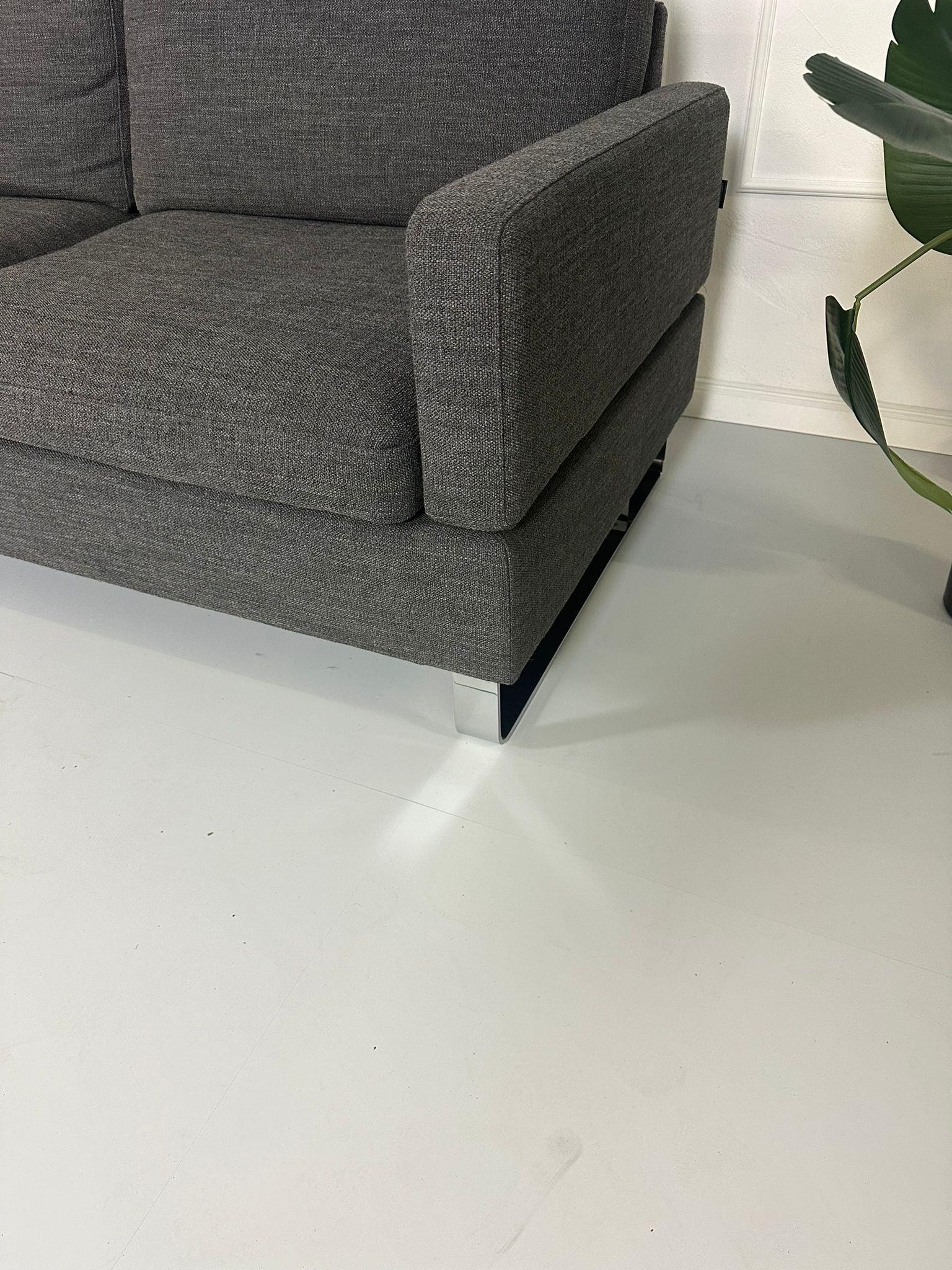 Gebrauchtes Brühl Alba Stoff Sofa in Anthrazit vor einer Wand, stilvoll und modern eingerichtet.