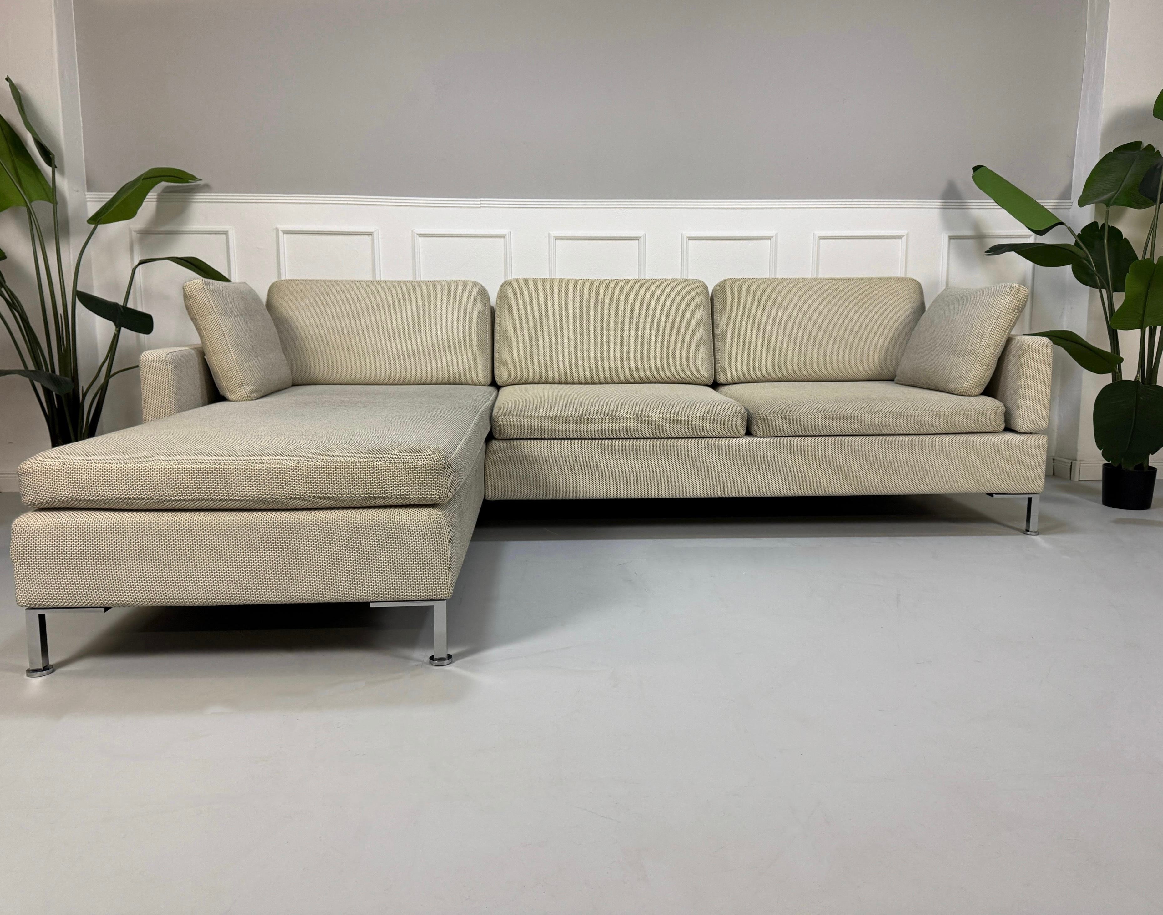 Gebrauchtes beiges Brühl Alba Designer Stoff Sofa vor einer Wand, stilvoll und modern eingerichtet.