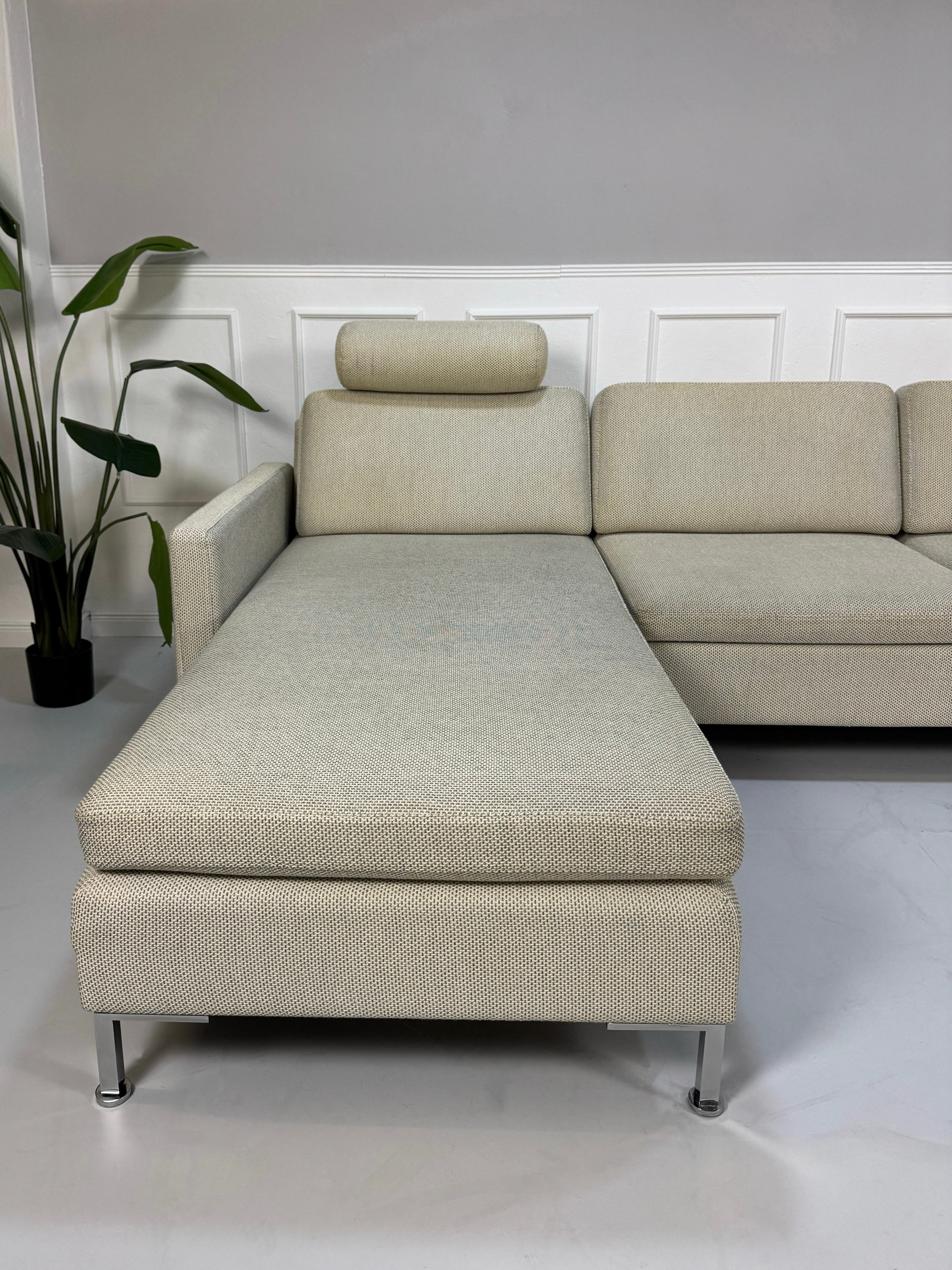 Gebrauchtes beiges Brühl Alba Designer Stoff Sofa vor einer Wand, stilvoll und modern eingerichtet.