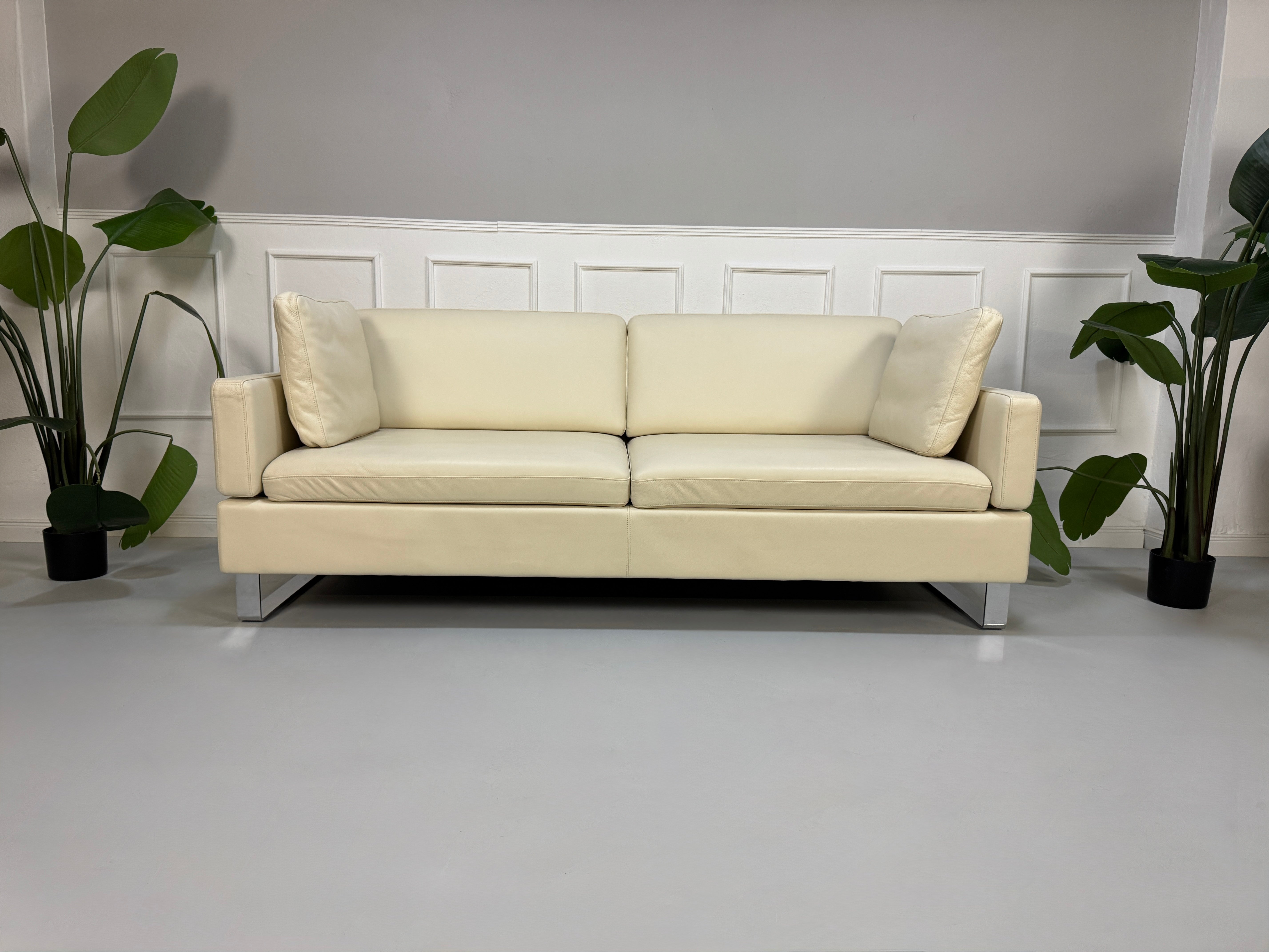 Gebrauchtes beiges Ledersofa Brühl Modell Alba vor einer modernen Wand
