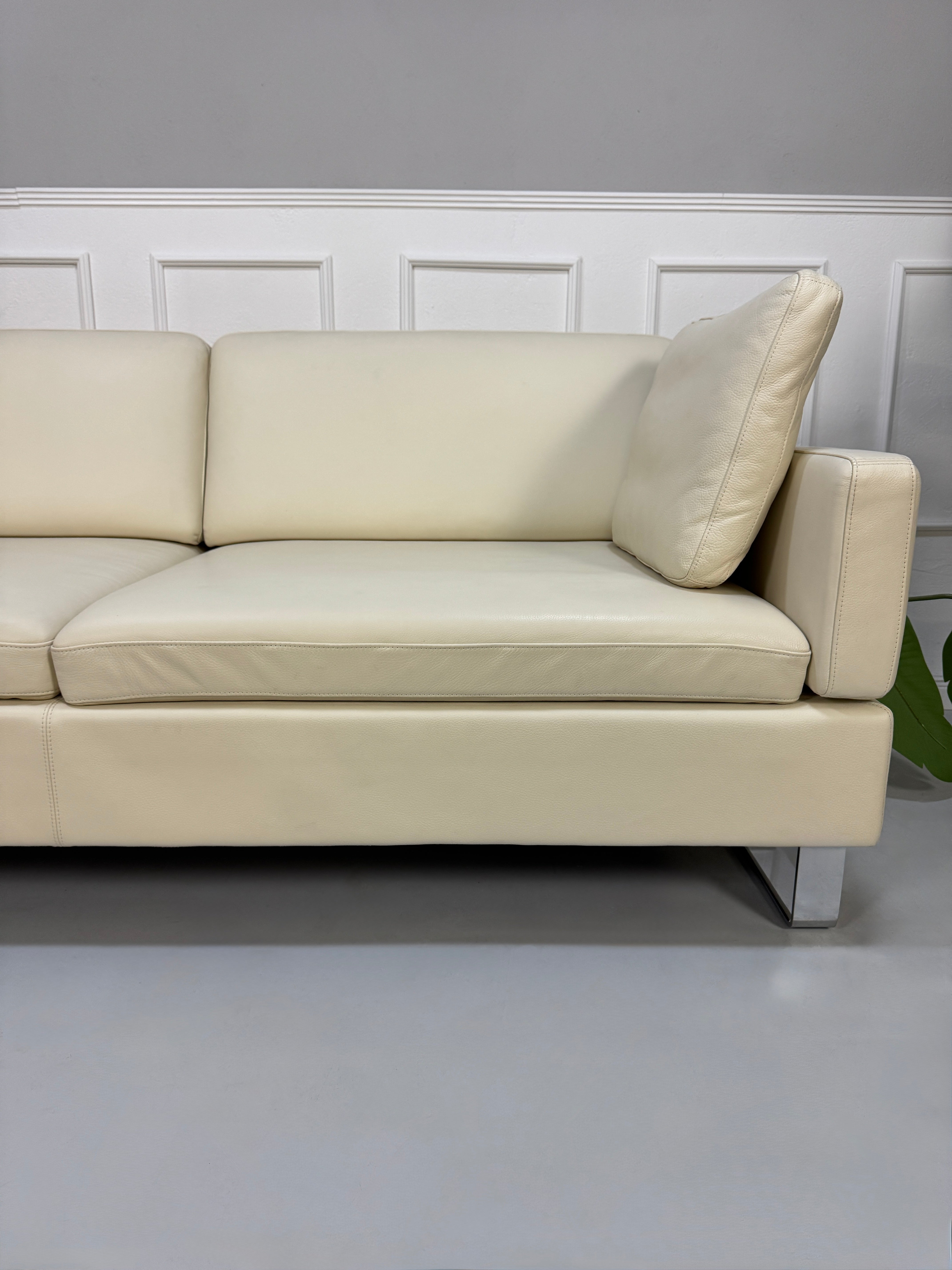 Gebrauchtes beiges Ledersofa Brühl Modell Alba vor einer modernen Wand