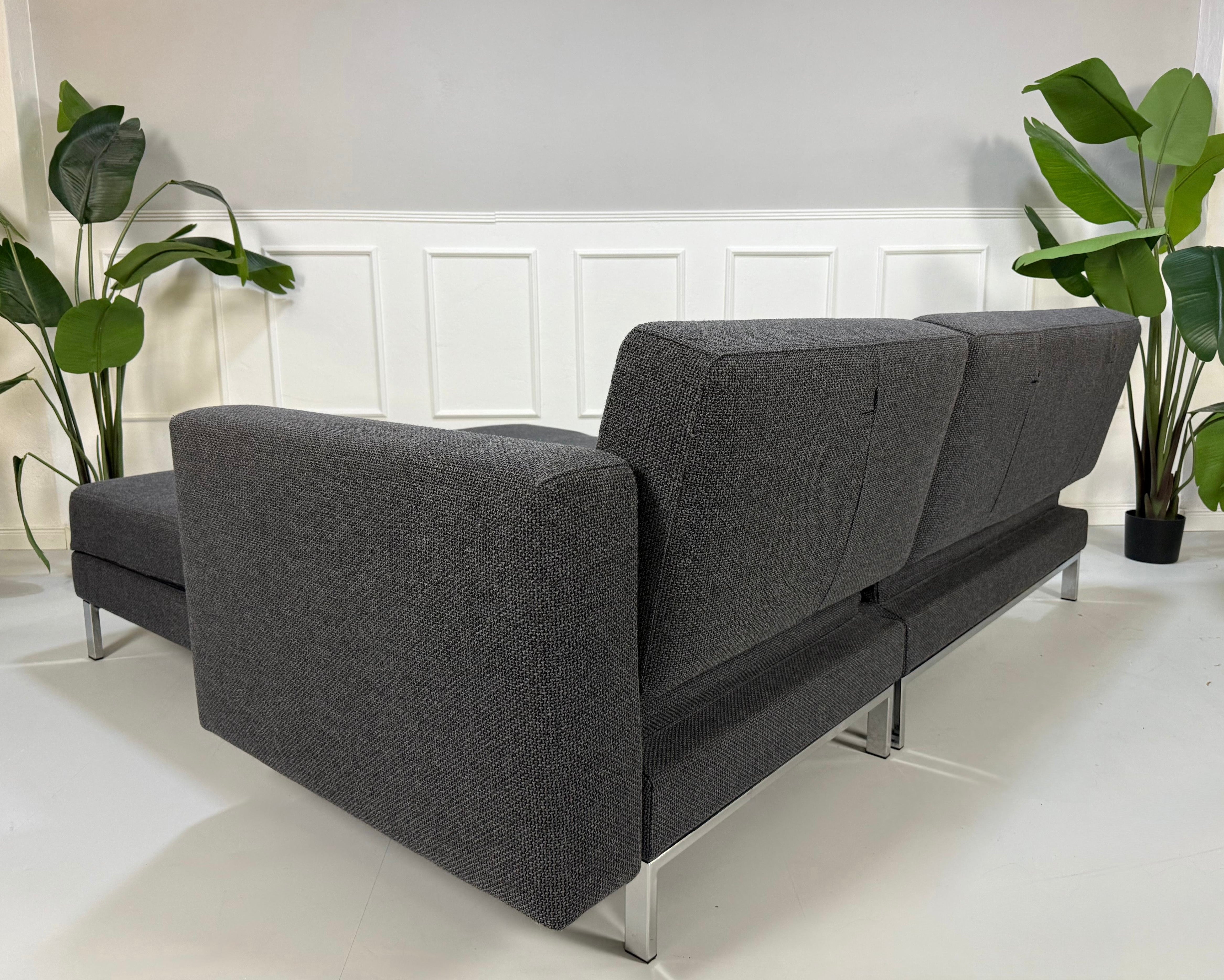 Ausstellungsstück Brühl Fourtwo Grau  Designer Stoff Sofa vor einer Wand, stilvoll und modern eingerichtet.