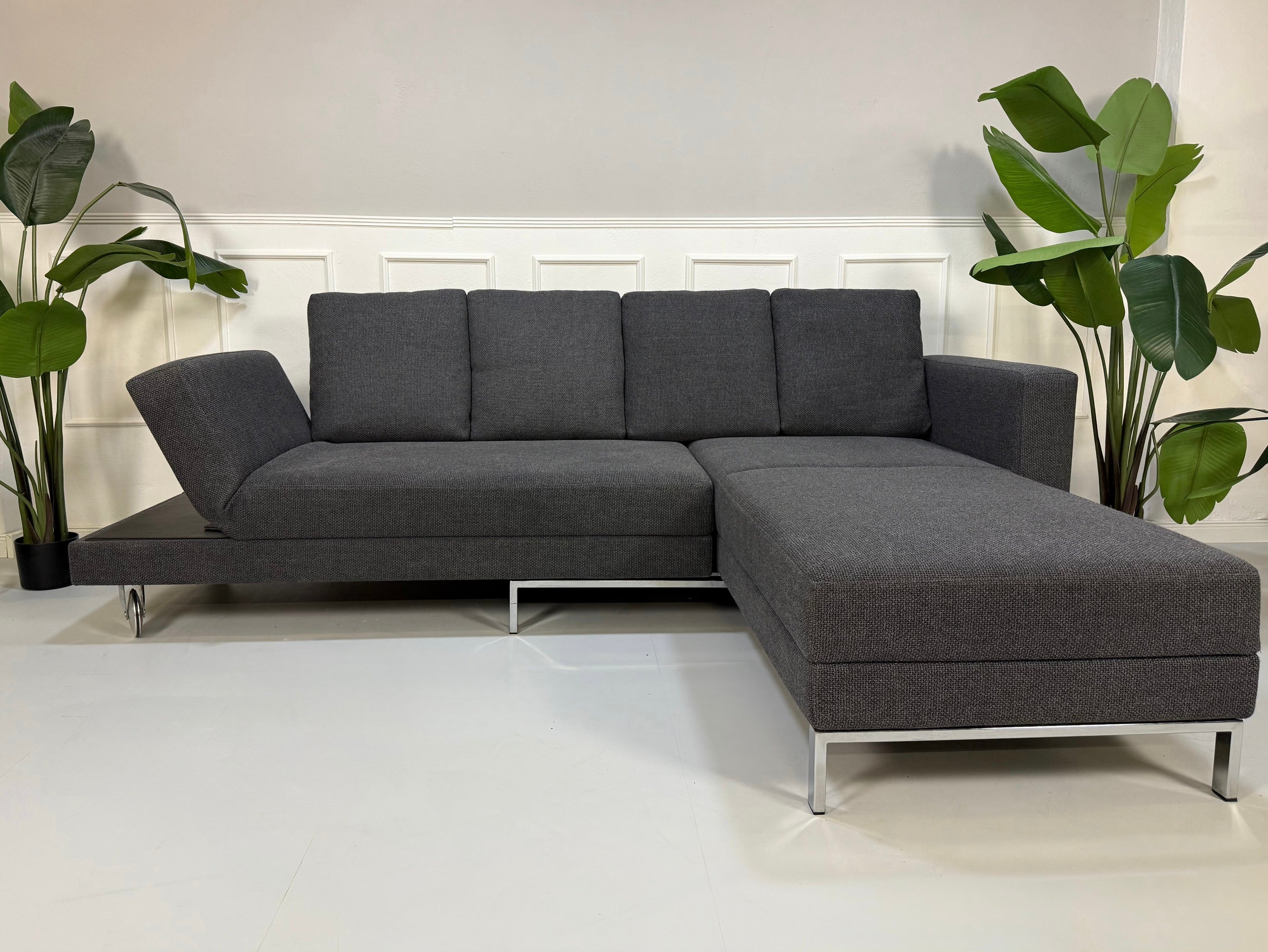 Ausstellungsstück Brühl Fourtwo Grau  Designer Stoff Sofa vor einer Wand, stilvoll und modern eingerichtet.