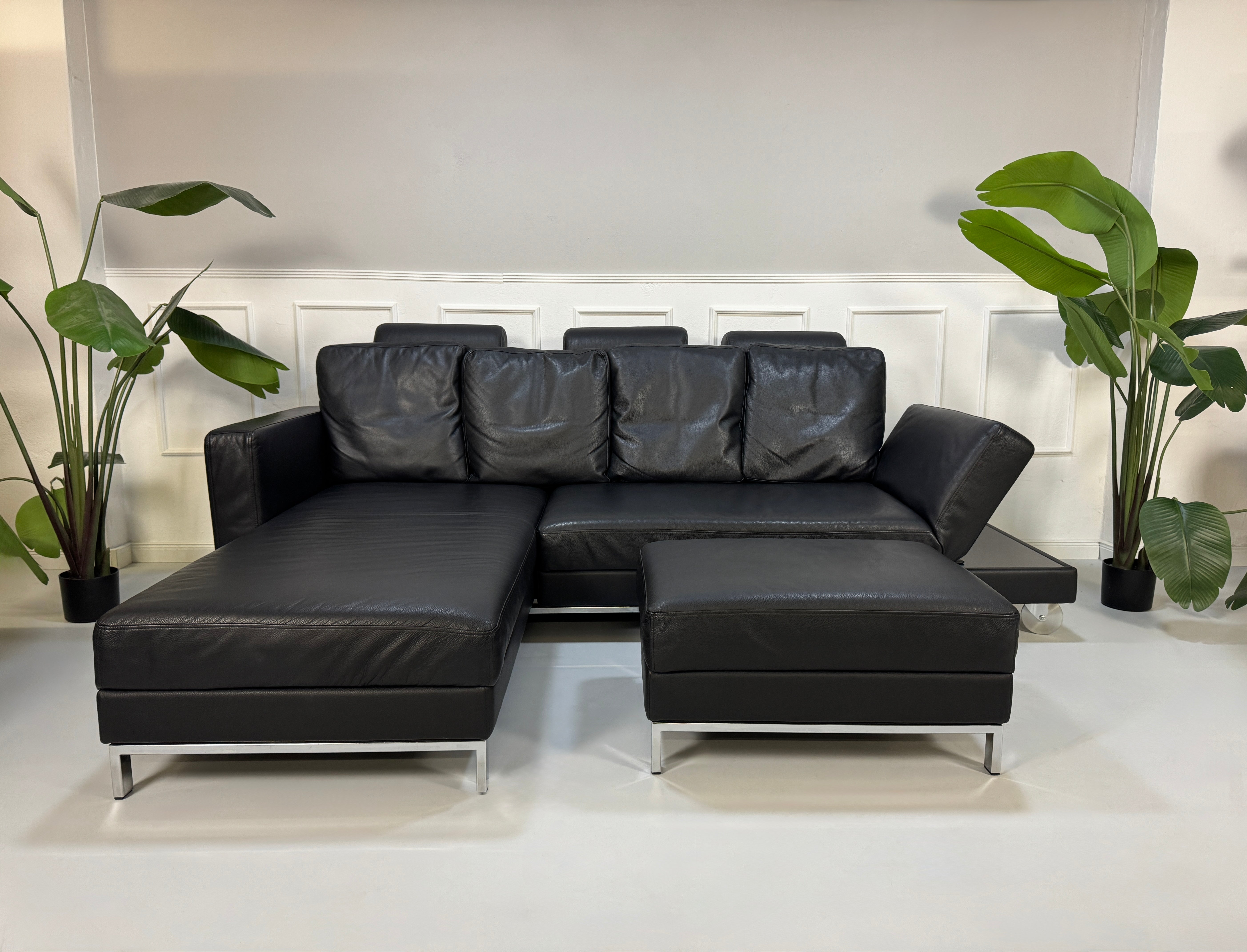 Brühl FourTwo Modell in der Farbe Schwarz Designer Leder Sofa vor einer Wand, stilvoll und modern eingerichtet.