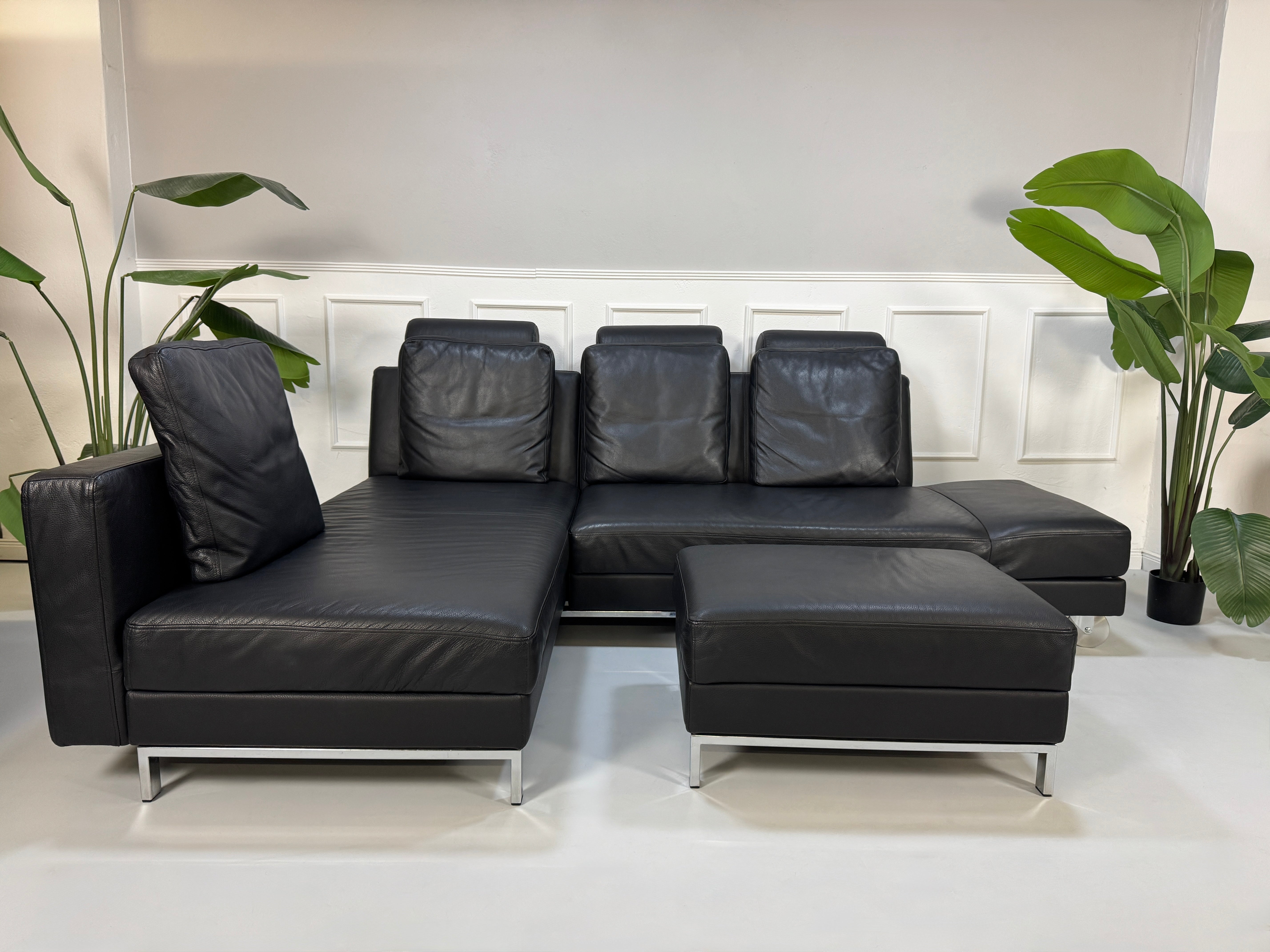 Brühl FourTwo Modell in der Farbe Schwarz Designer Leder Sofa vor einer Wand, stilvoll und modern eingerichtet.