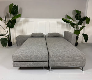 Gebrauchtes Brühl FourTwo Stoff Sofa in der Farbe Grau vor einer Wand, stilvoll und modern eingerichtet.