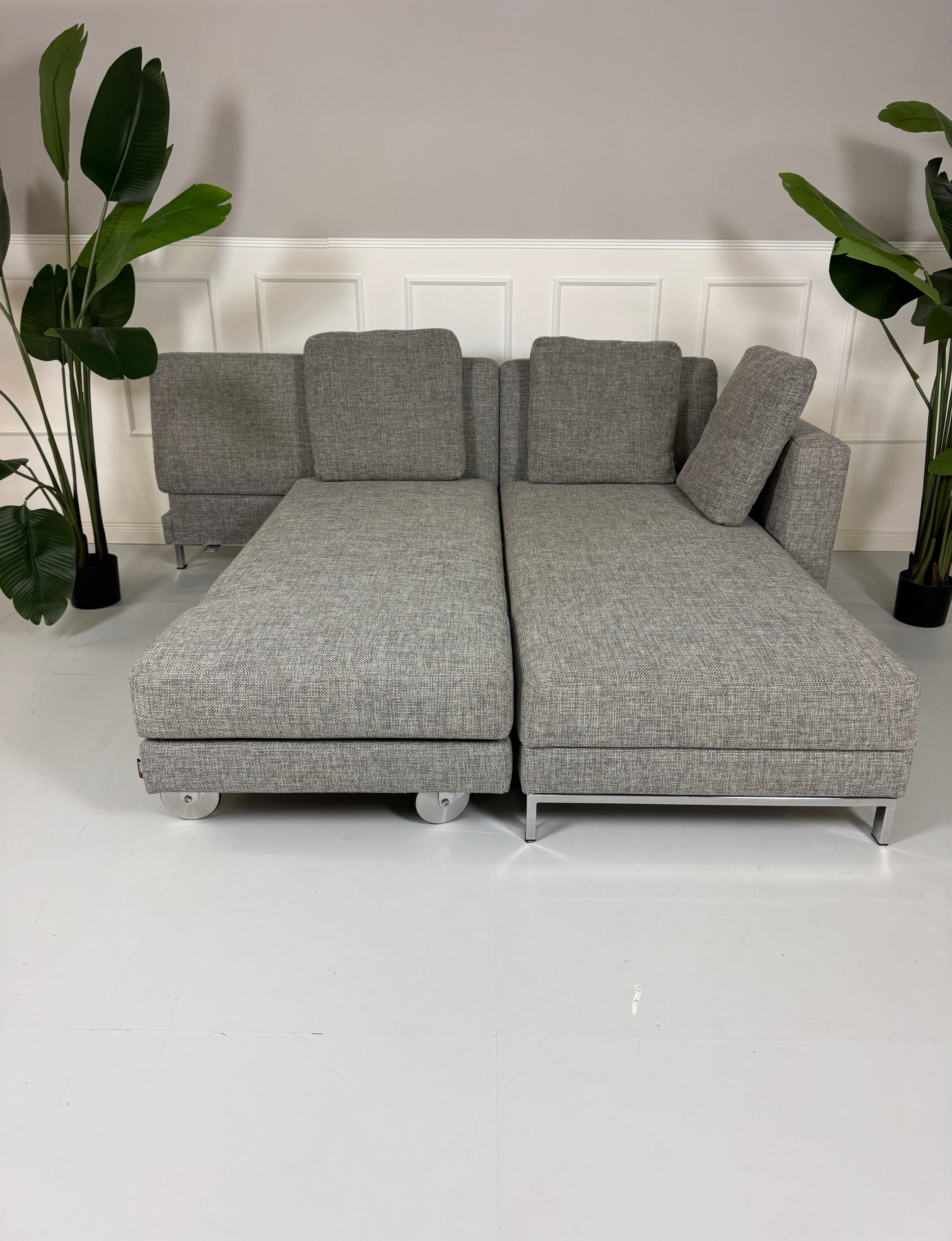 Gebrauchtes Brühl FourTwo Stoff Sofa in der Farbe Grau vor einer Wand, stilvoll und modern eingerichtet.