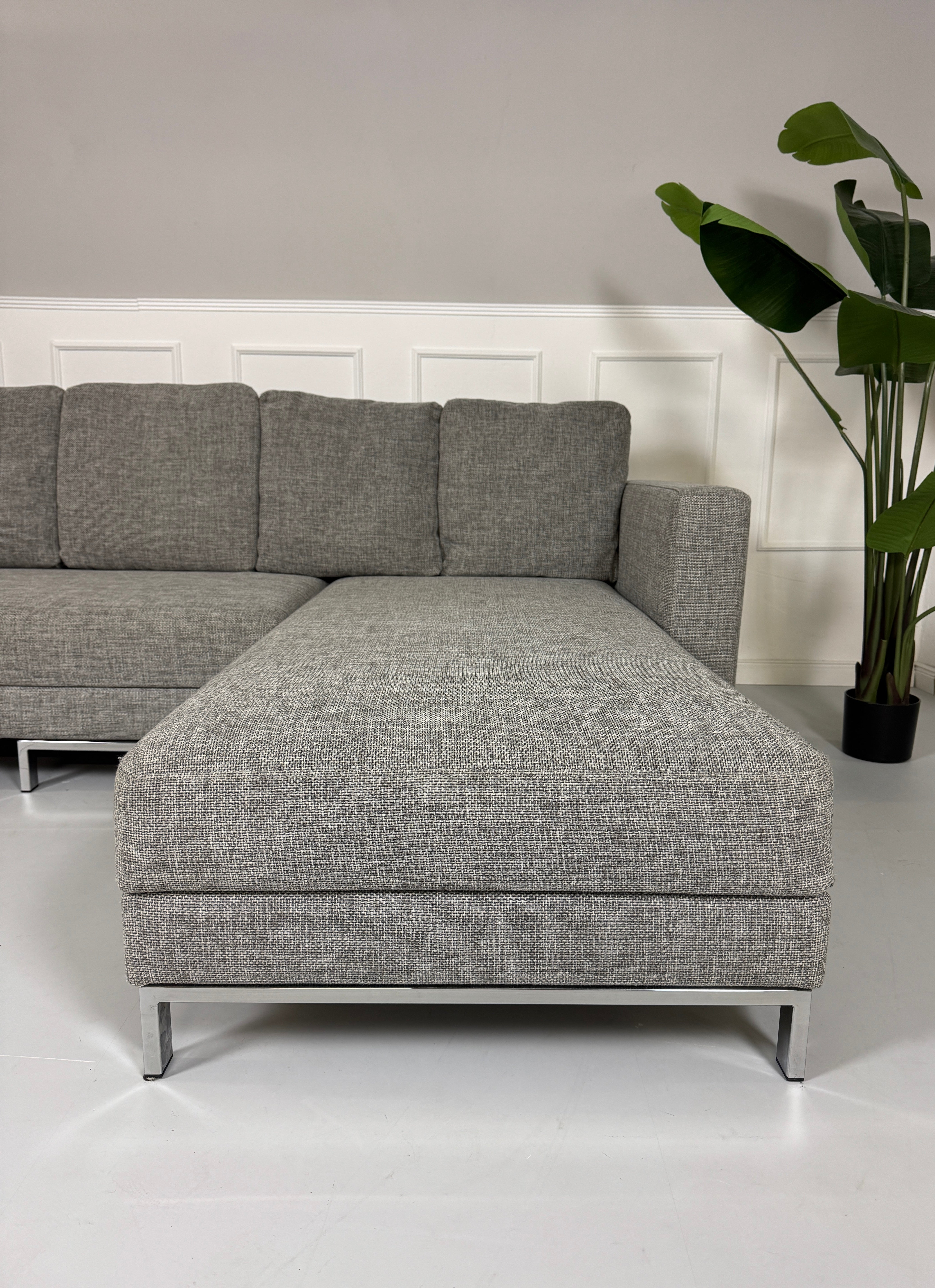 Gebrauchtes Brühl FourTwo Stoff Sofa in der Farbe Grau vor einer Wand, stilvoll und modern eingerichtet.