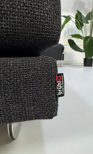 Gebrauchtes graues Brühl Fourtwo Designer Stoff Sofa vor einer Wand, stilvoll und modern eingerichtet.