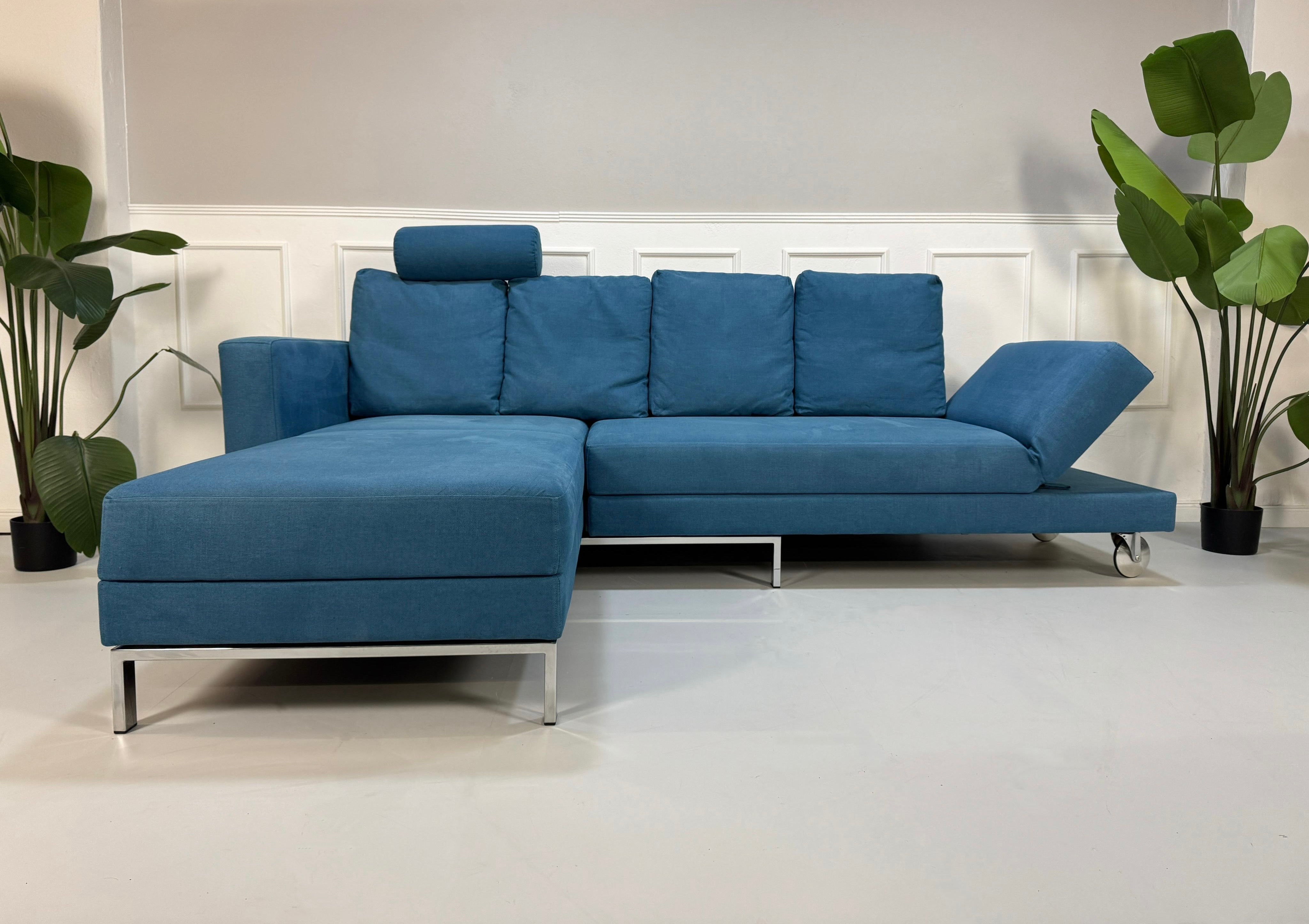 Gebrauchtes blaues Brühl Fourtwo Designer Stoff Sofa vor einer Wand, stilvoll und modern eingerichtet.