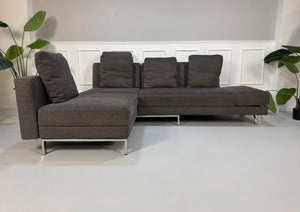 Gebrauchtes grau braunes Brühl Fourtwo Designer Stoff Sofa vor einer Wand, stilvoll und modern eingerichtet.