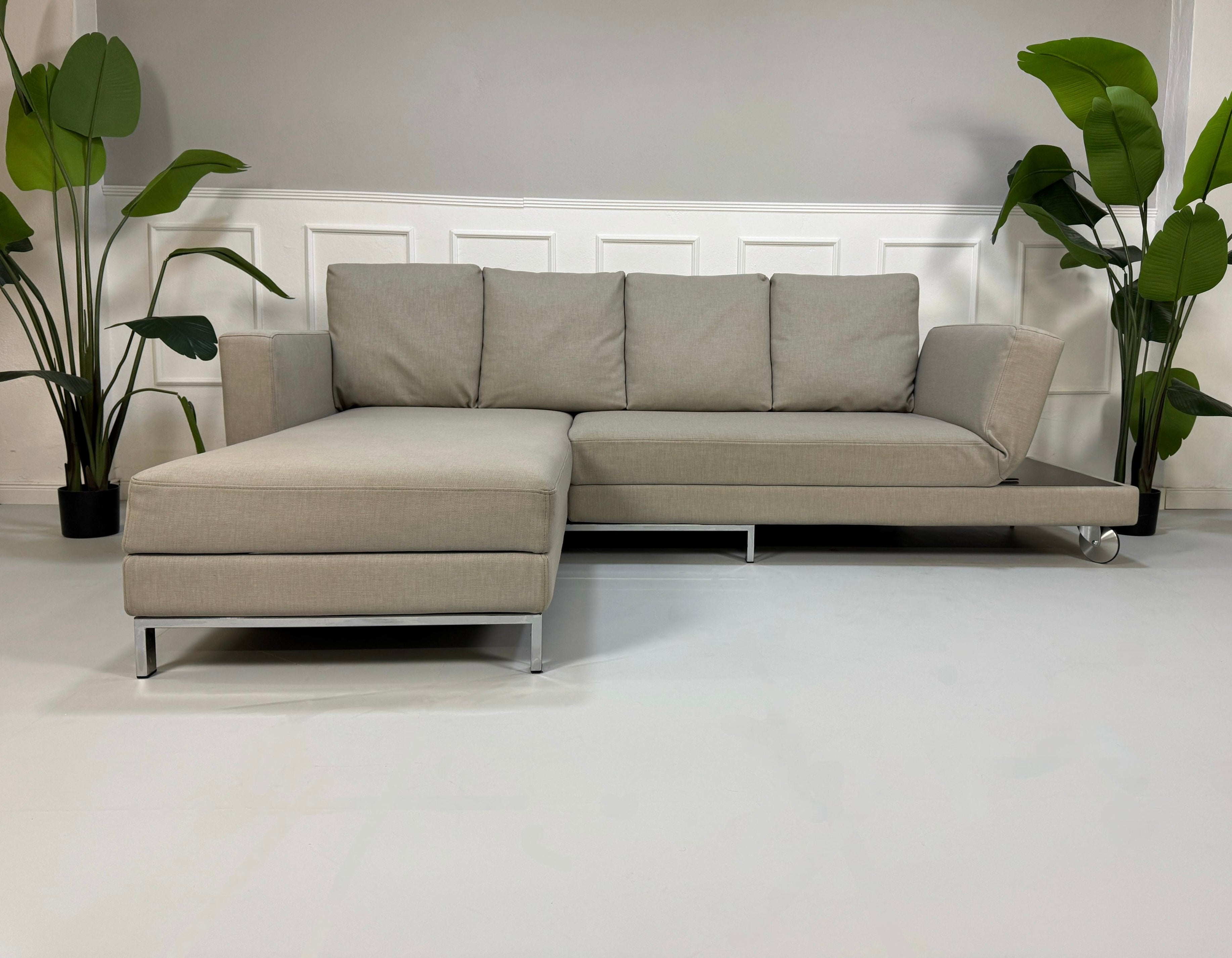 Gebrauchtes graues Brühl Four Two Designer Stoff Sofa vor einer Wand, stilvoll und modern eingerichtet.