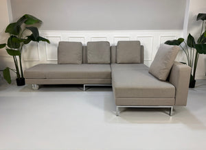 Gebrauchtes graues Brühl Fourtwo Designer Stoff Sofa vor einer Wand, stilvoll und modern eingerichtet.