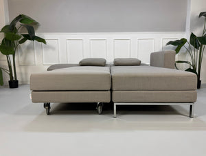 Gebrauchtes graues Brühl Fourtwo Designer Stoff Sofa vor einer Wand, stilvoll und modern eingerichtet.