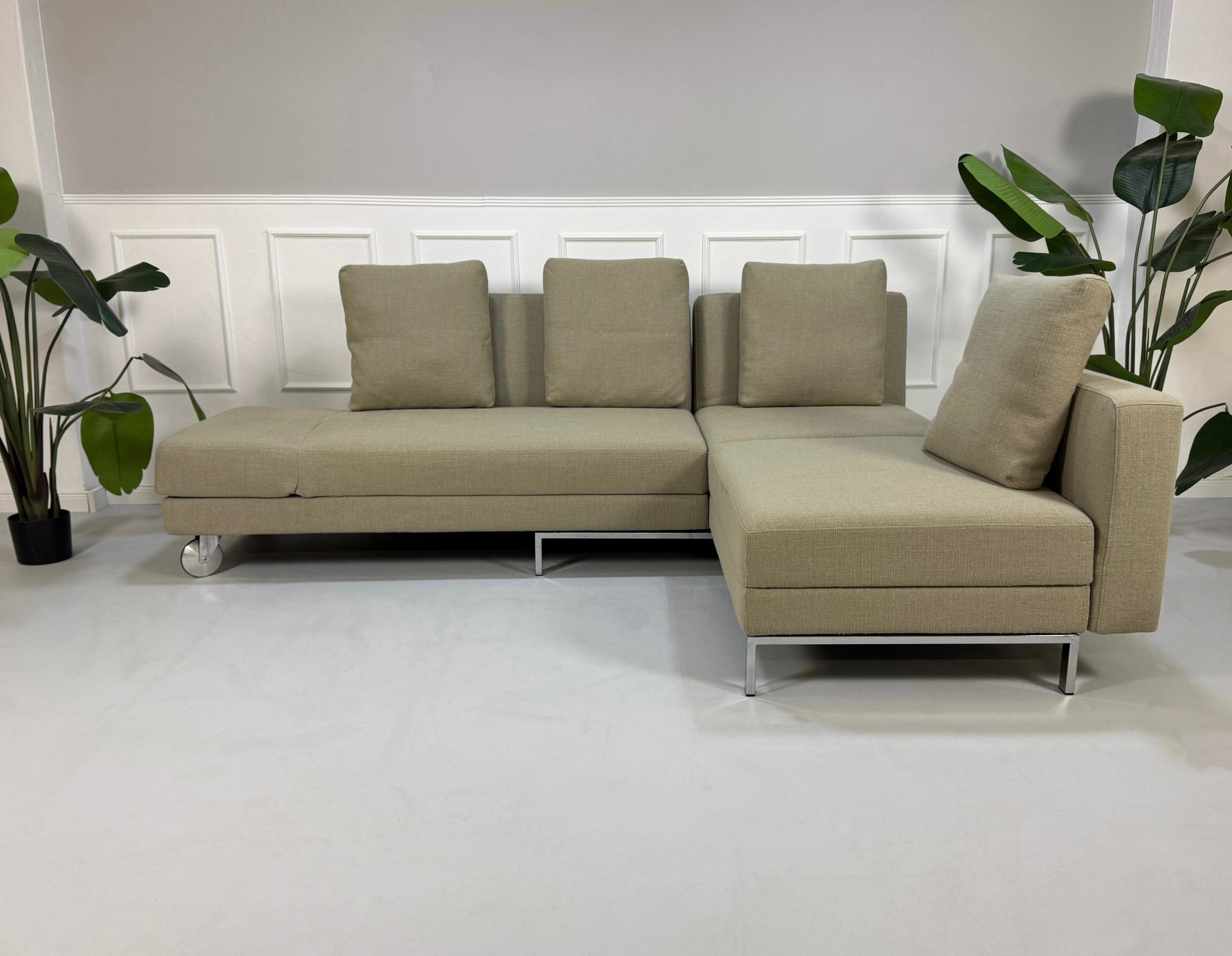 Gebrauchtes graues Brühl Fourtwo Designer Stoff Sofa vor einer Wand, stilvoll und modern eingerichtet.