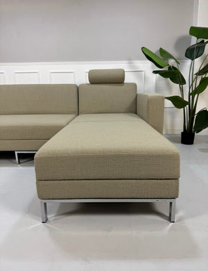 Gebrauchtes graues Brühl Fourtwo Designer Stoff Sofa vor einer Wand, stilvoll und modern eingerichtet.