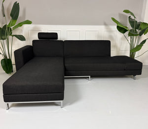 Erneuertes schwarzes Brühl Designer Stoff Sofa vor einer Wand, stilvoll und modern eingerichtet.
