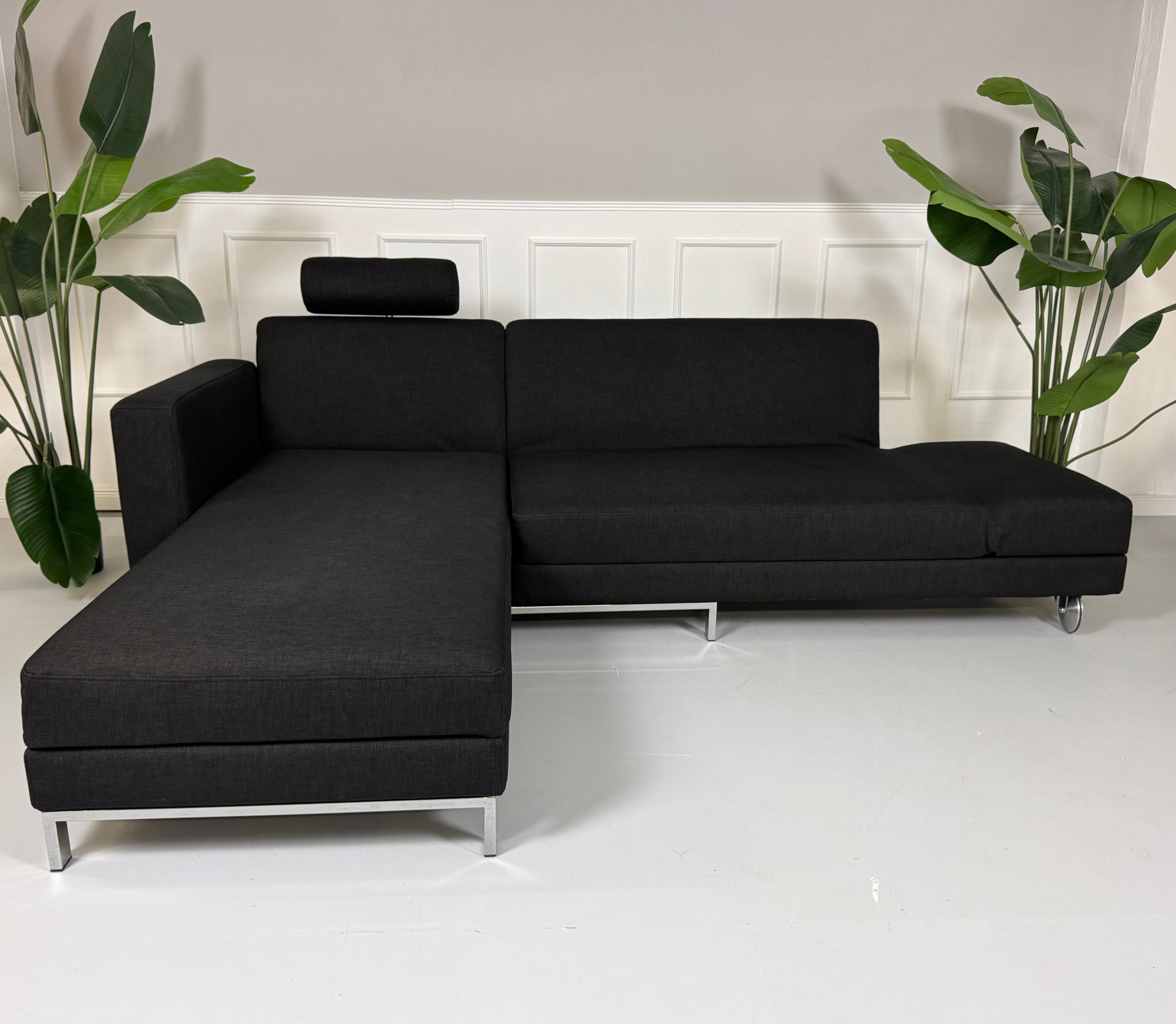 Gebrauchtes Brühl FourTwo Stoff Sofa in der Farbe Schwarz vor einer Wand, stilvoll und modern eingerichtet.