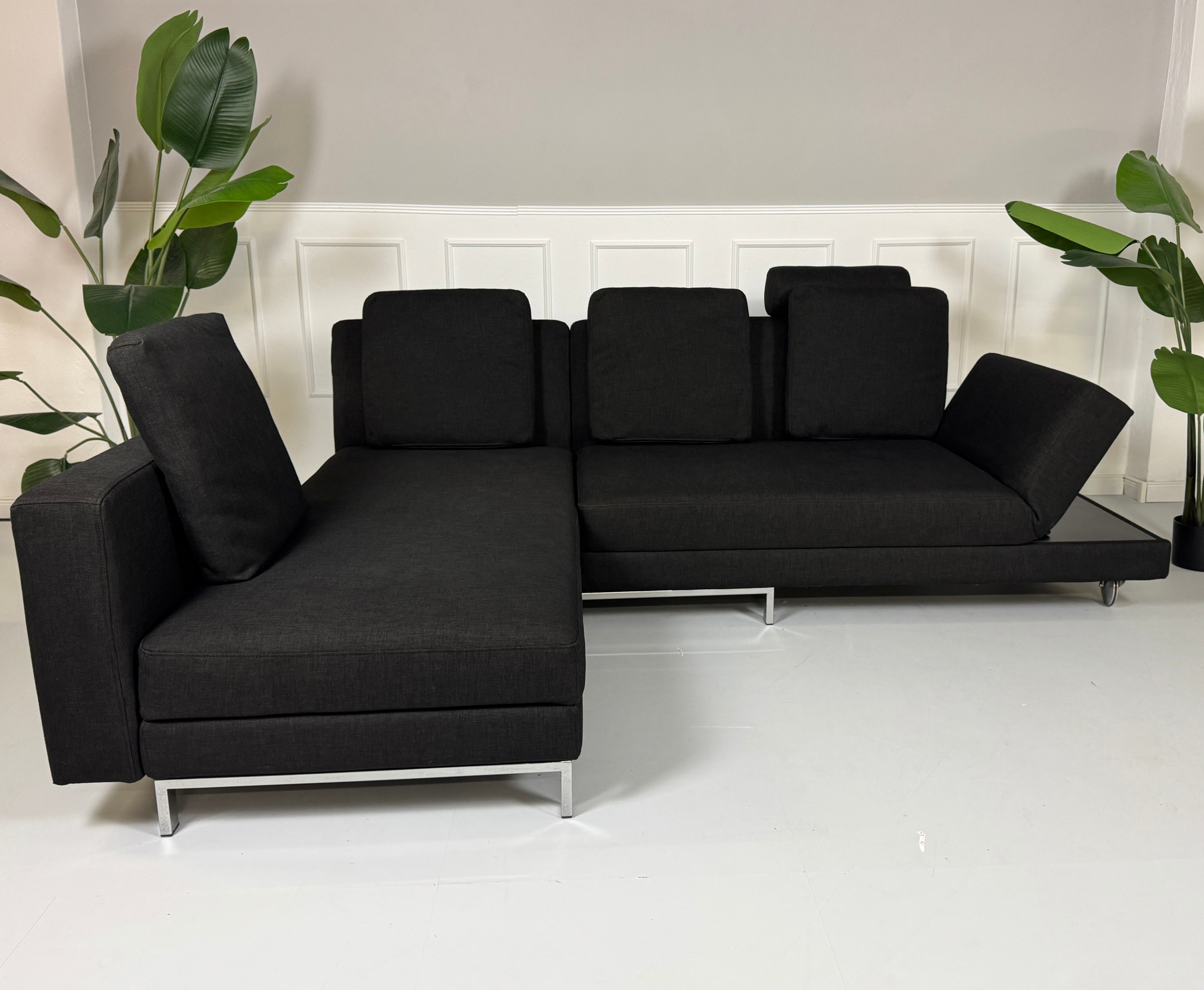 Erneuertes schwarzes Brühl Designer Stoff Sofa vor einer Wand, stilvoll und modern eingerichtet.
