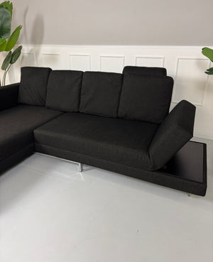 Erneuertes schwarzes Brühl Designer Stoff Sofa vor einer Wand, stilvoll und modern eingerichtet.