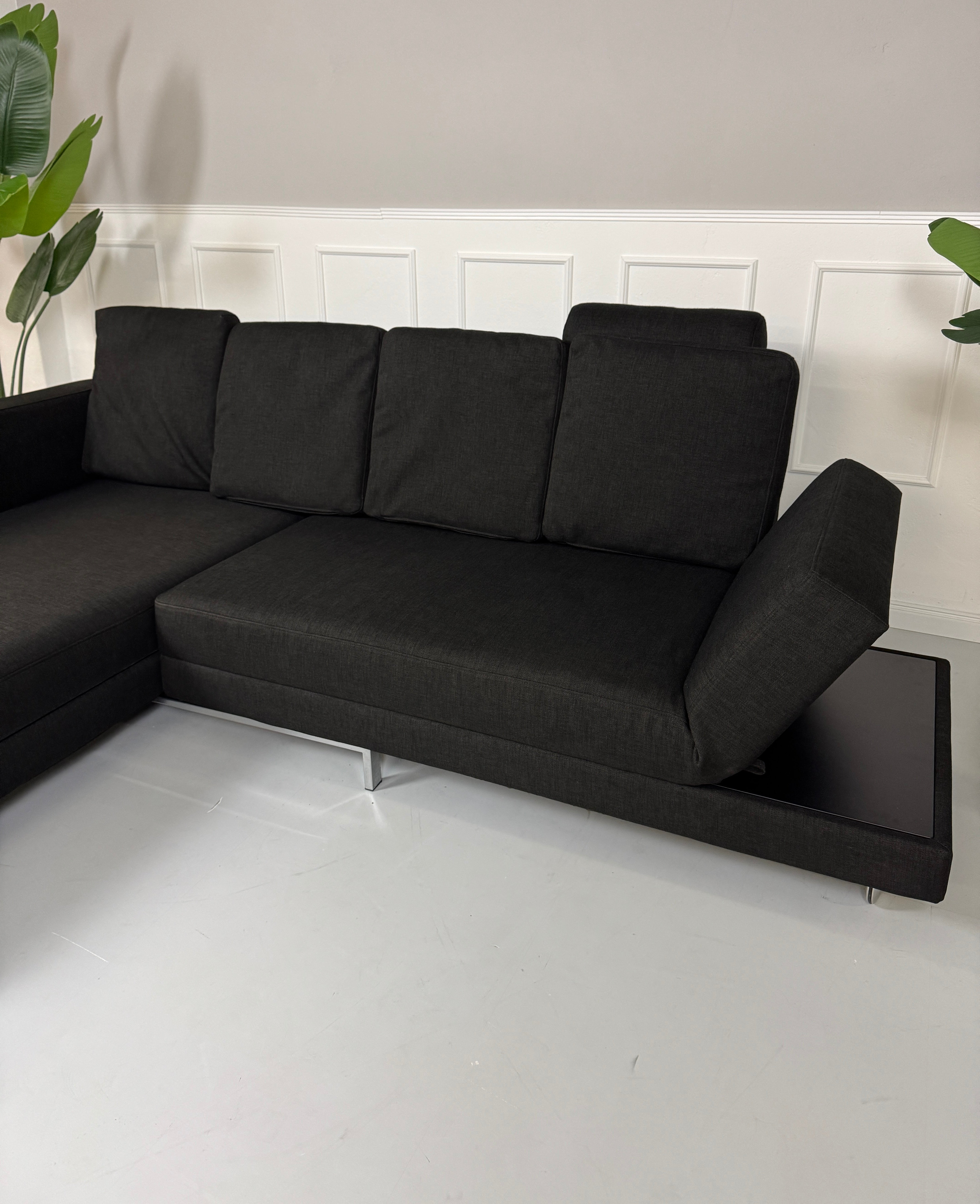 Erneuertes schwarzes Brühl Designer Stoff Sofa vor einer Wand, stilvoll und modern eingerichtet.