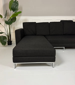 Erneuertes schwarzes Brühl Designer Stoff Sofa vor einer Wand, stilvoll und modern eingerichtet.