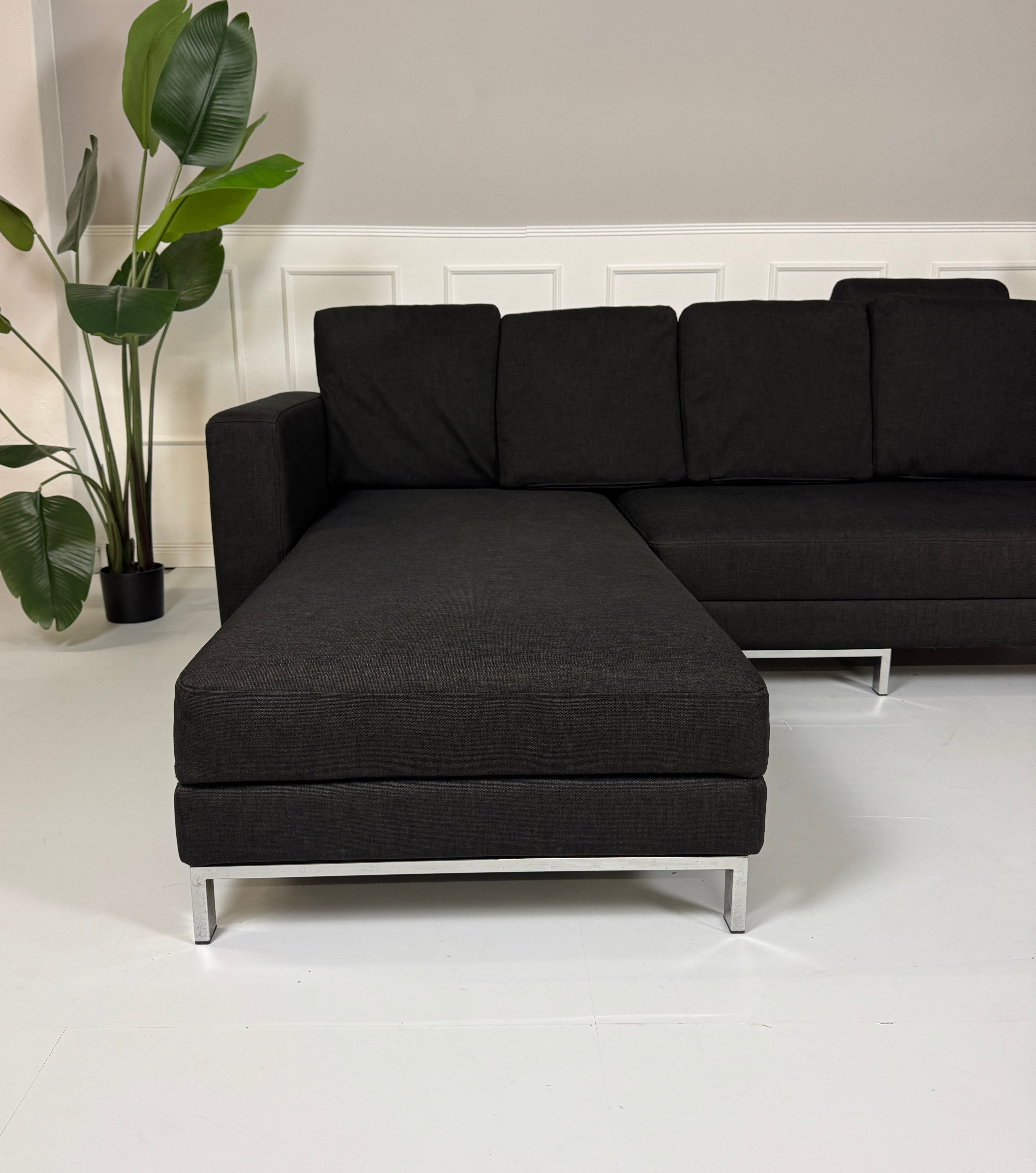 Erneuertes schwarzes Brühl Designer Stoff Sofa vor einer Wand, stilvoll und modern eingerichtet.