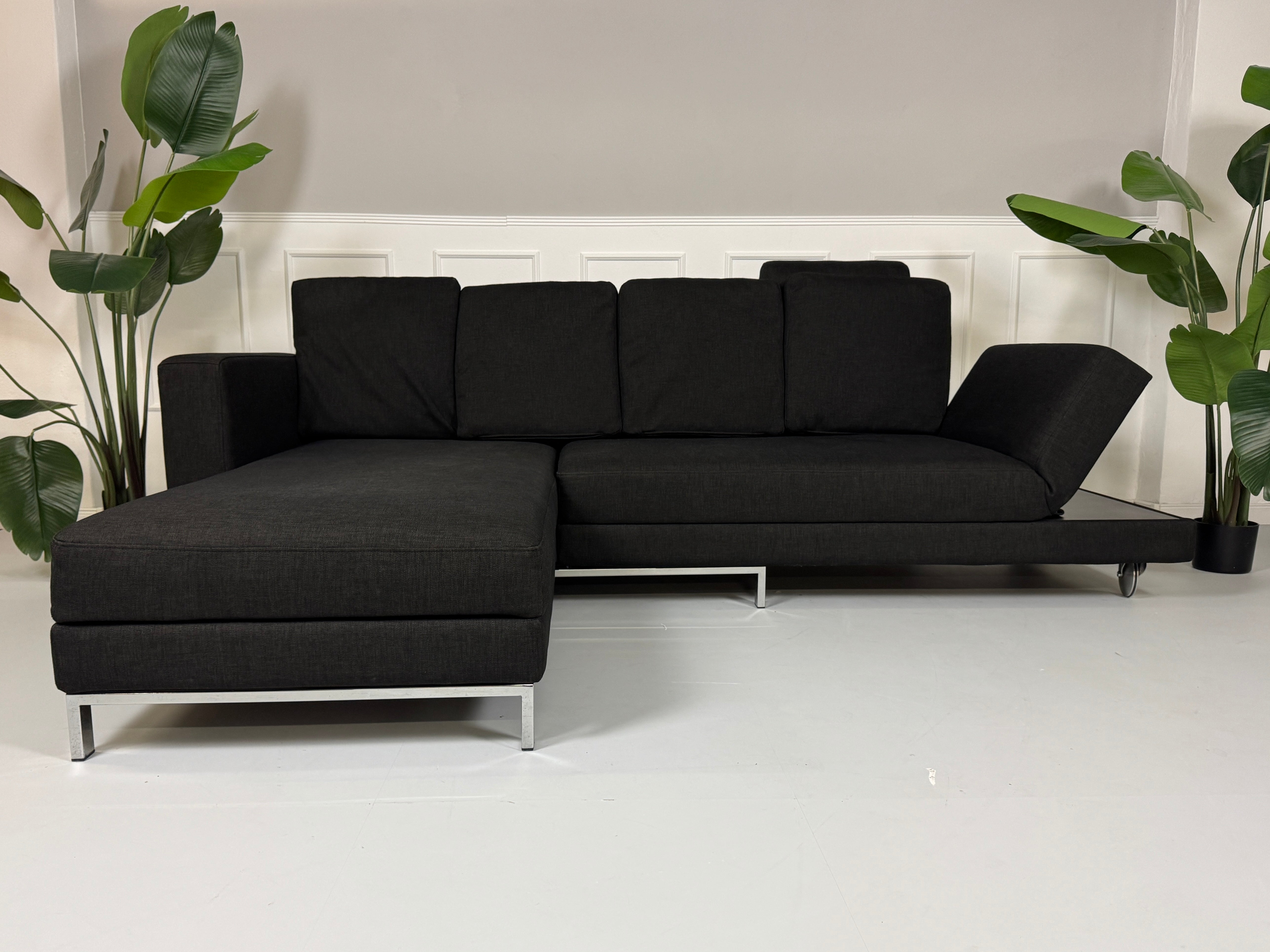 Erneuertes schwarzes Brühl Designer Stoff Sofa vor einer Wand, stilvoll und modern eingerichtet.