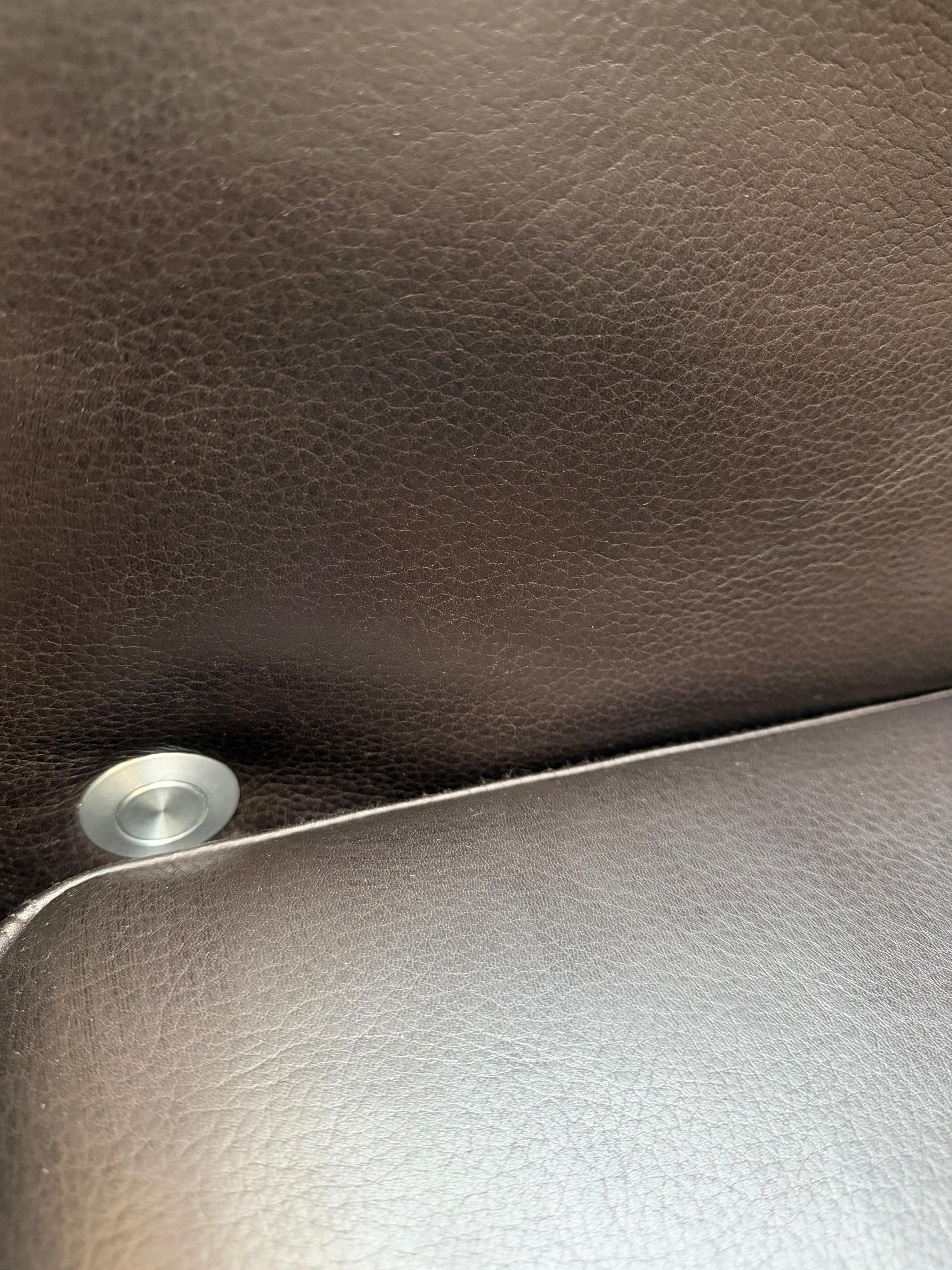 Gebrauchtes braunes Ledersofa Brühl Modell Moule 3 Sitzer vor einer modernen Wand.