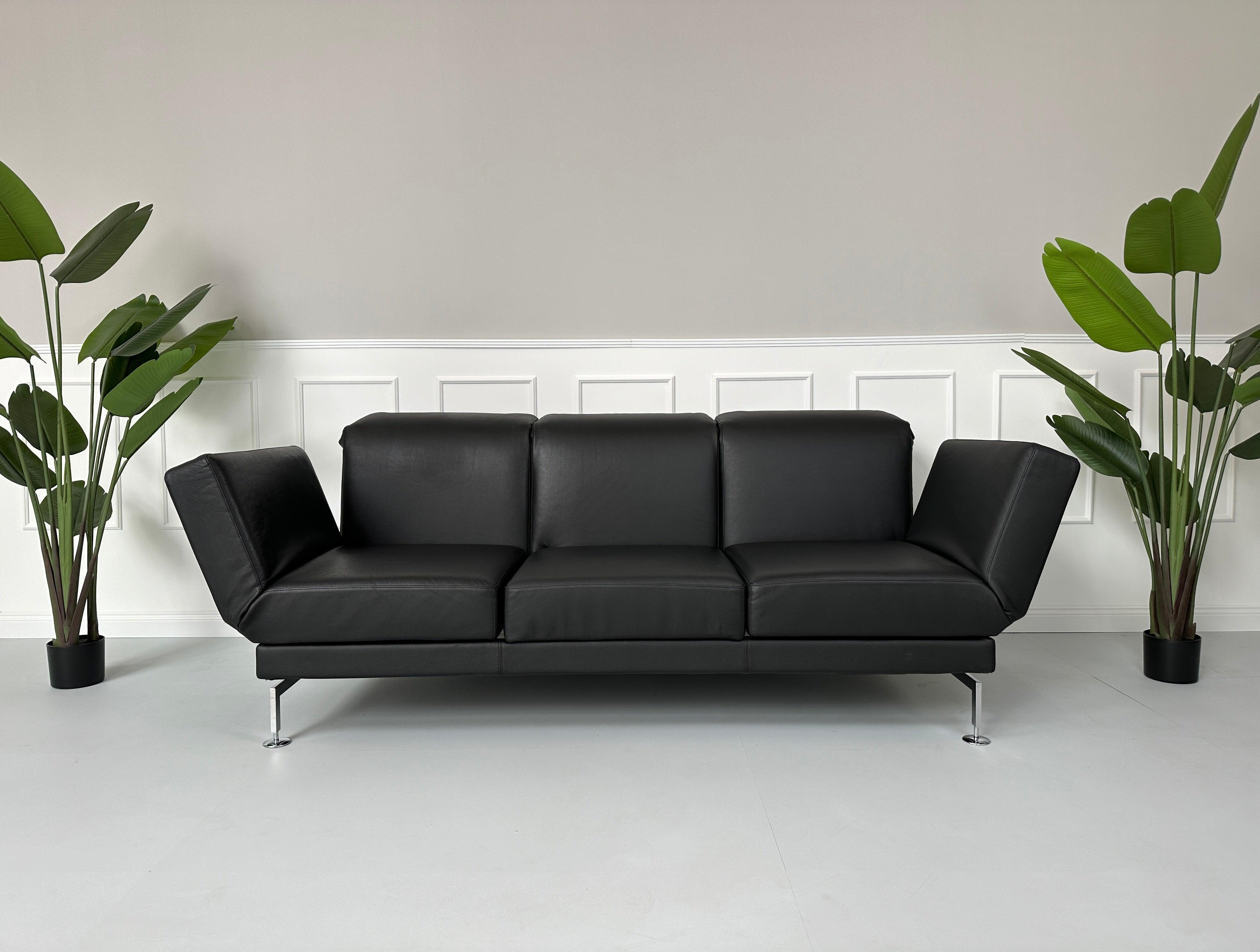 Gebrauchtes Brühl Moule Small 3-Sitzer Sofa Leder in der Farbe Schwarz vor einer Wand, stilvoll und modern eingerichtet.