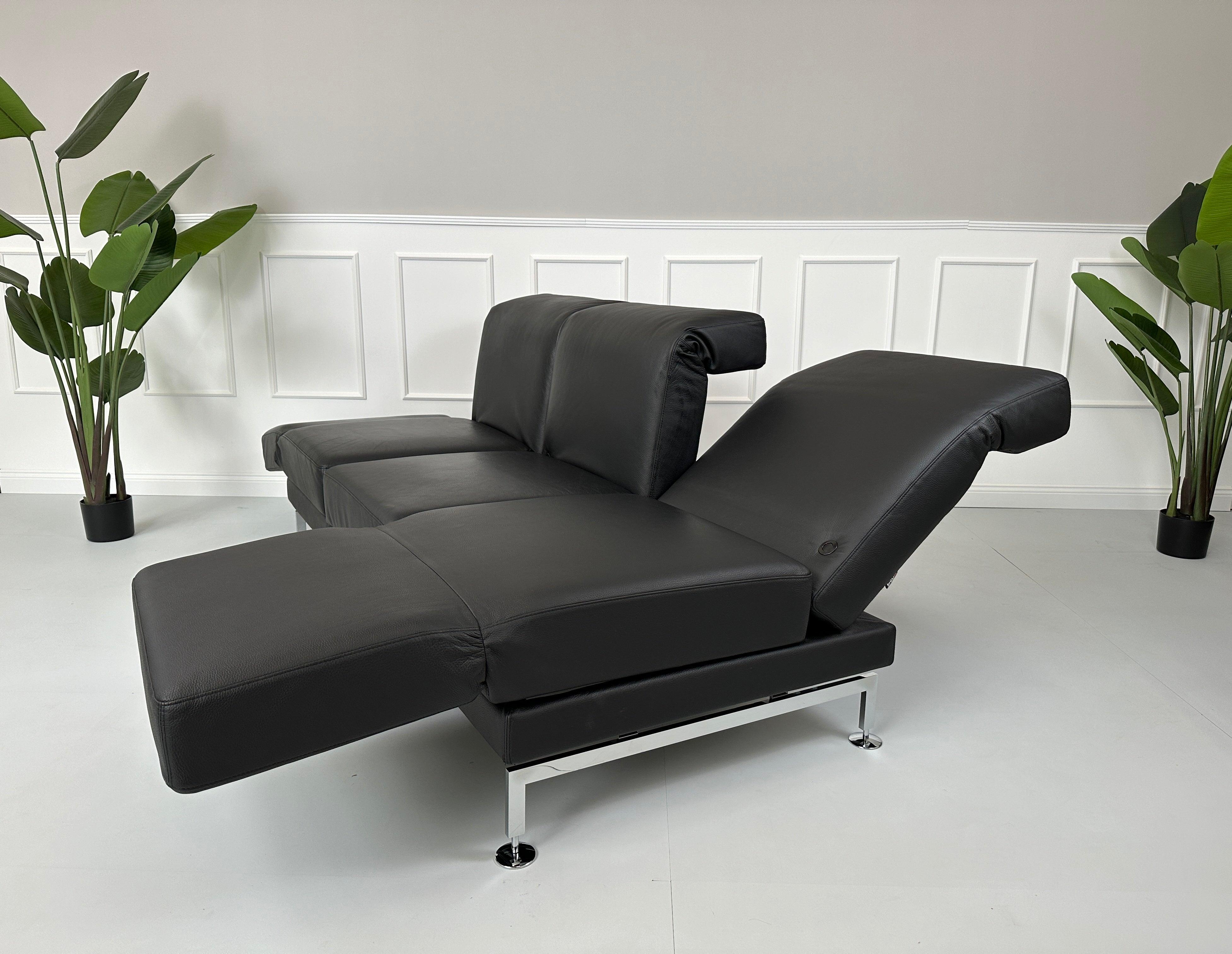 Gebrauchtes Brühl Moule Small 3-Sitzer Sofa Leder in der Farbe Schwarz vor einer Wand, stilvoll und modern eingerichtet.