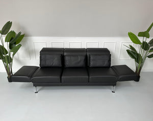 Gebrauchtes Brühl Moule Small 3-Sitzer Sofa Leder in der Farbe Schwarz vor einer Wand, stilvoll und modern eingerichtet.