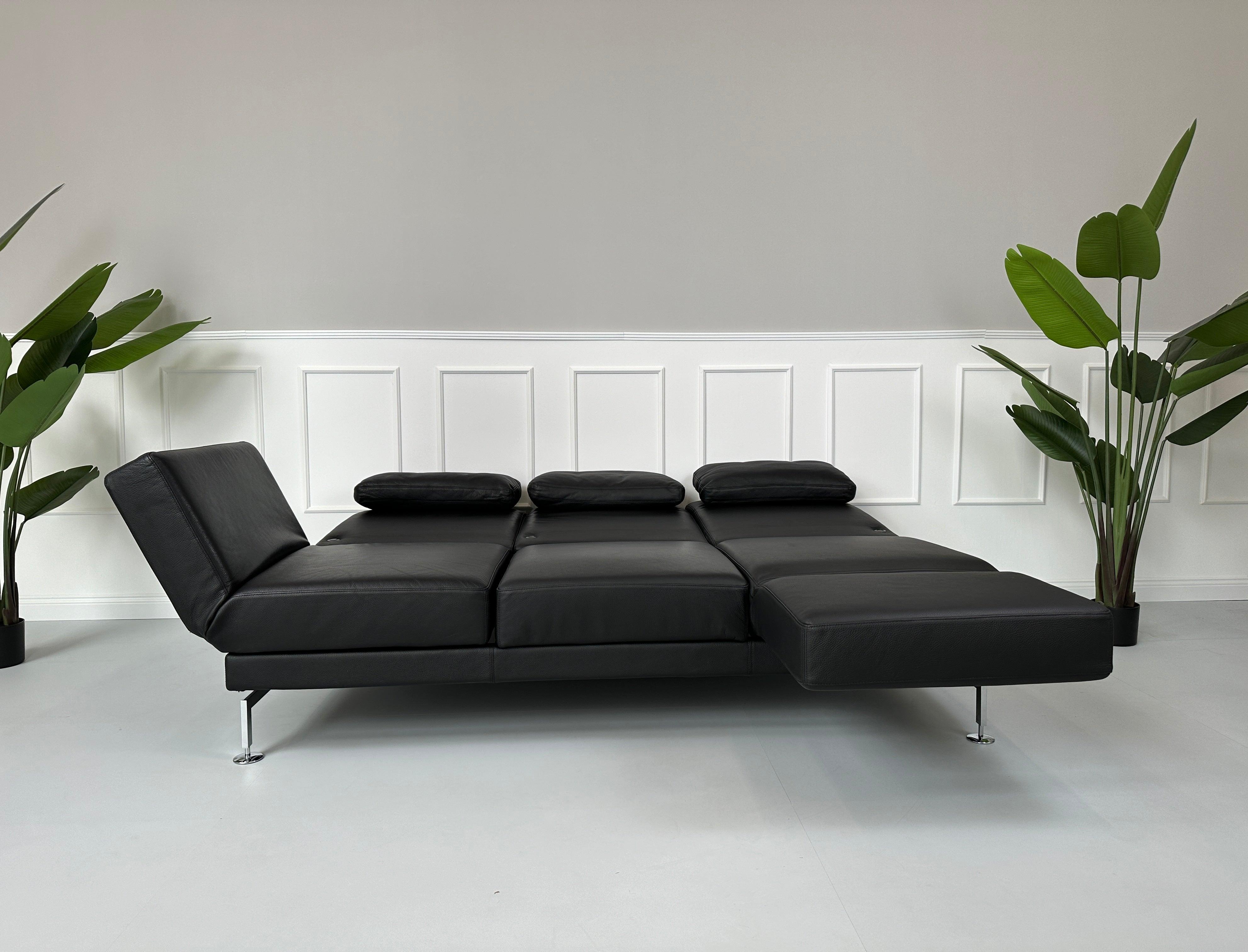 Gebrauchtes Brühl Moule Small 3-Sitzer Sofa Leder in der Farbe Schwarz vor einer Wand, stilvoll und modern eingerichtet.