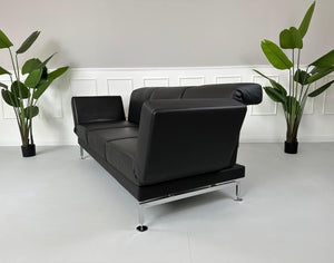 Gebrauchtes Brühl Moule Small 3-Sitzer Sofa Leder in der Farbe Schwarz vor einer Wand, stilvoll und modern eingerichtet.