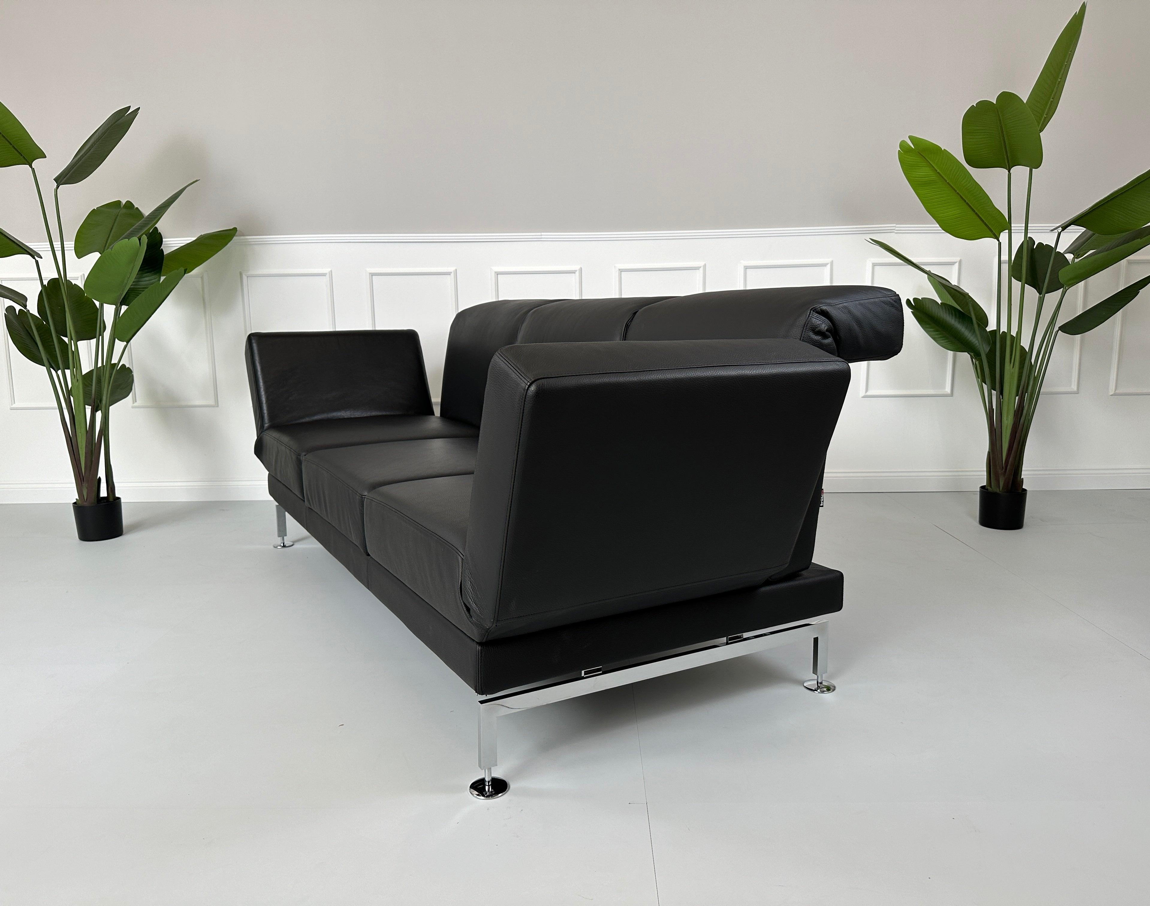 Gebrauchtes Brühl Moule Small 3-Sitzer Sofa Leder in der Farbe Schwarz vor einer Wand, stilvoll und modern eingerichtet.