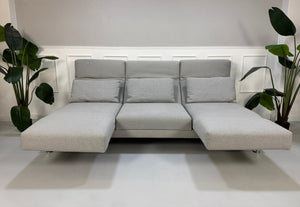 Gebrauchtes graues Brühl Moule Designer Stoff Sofa vor einer Wand, stilvoll und modern eingerichtet.