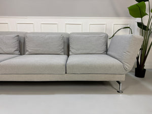 Gebrauchtes graues Brühl Moule Designer Stoff Sofa vor einer Wand, stilvoll und modern eingerichtet.