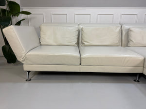 Gebrauchtes weißes Brühl Moule Designer Leder Sofa vor einer Wand, stilvoll und modern eingerichtet.