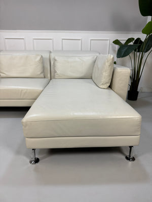 Gebrauchtes weißes Brühl Moule Designer Leder Sofa vor einer Wand, stilvoll und modern eingerichtet.
